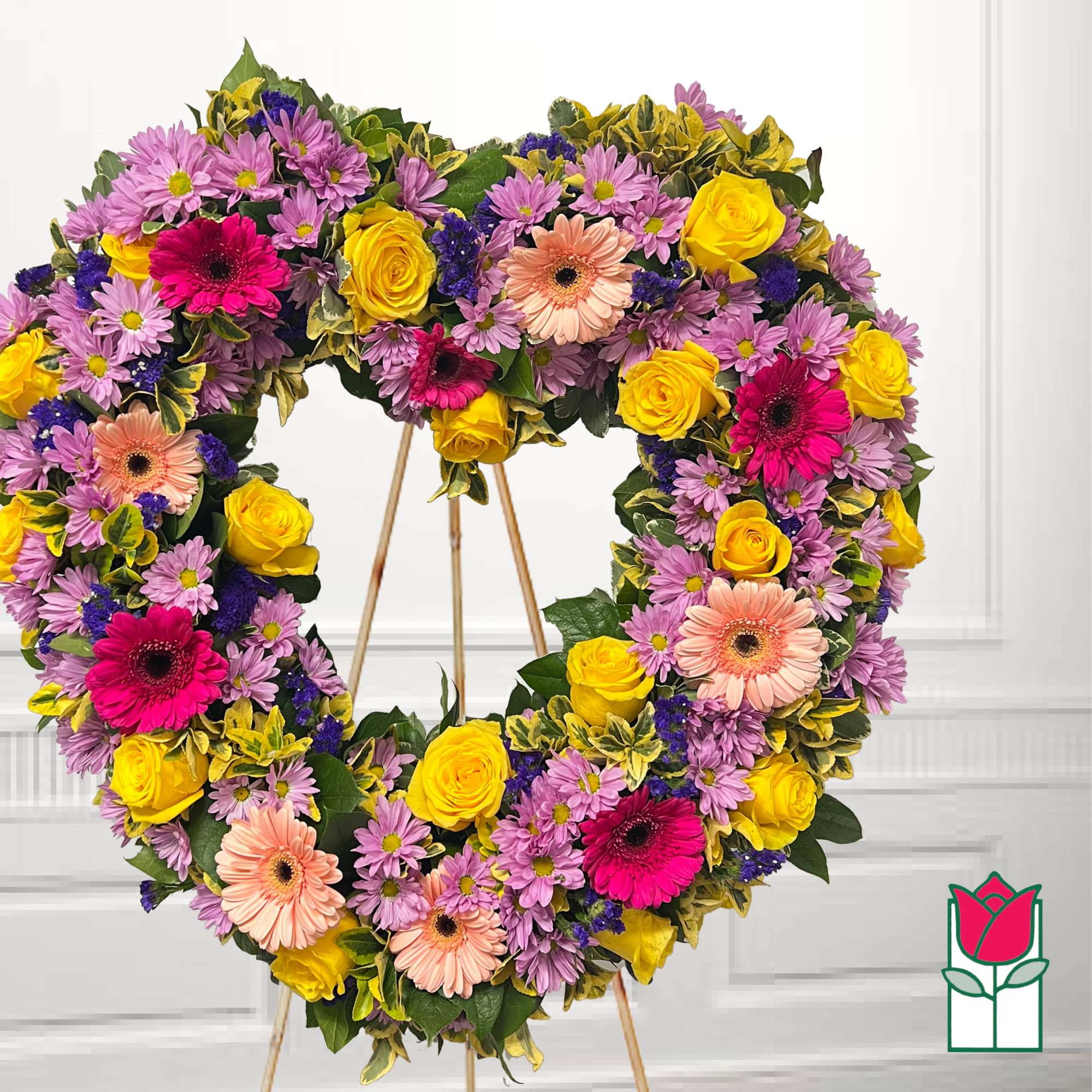 Heart-shaped floral wreath with yellow roses, pink gerberas, and purple daisies