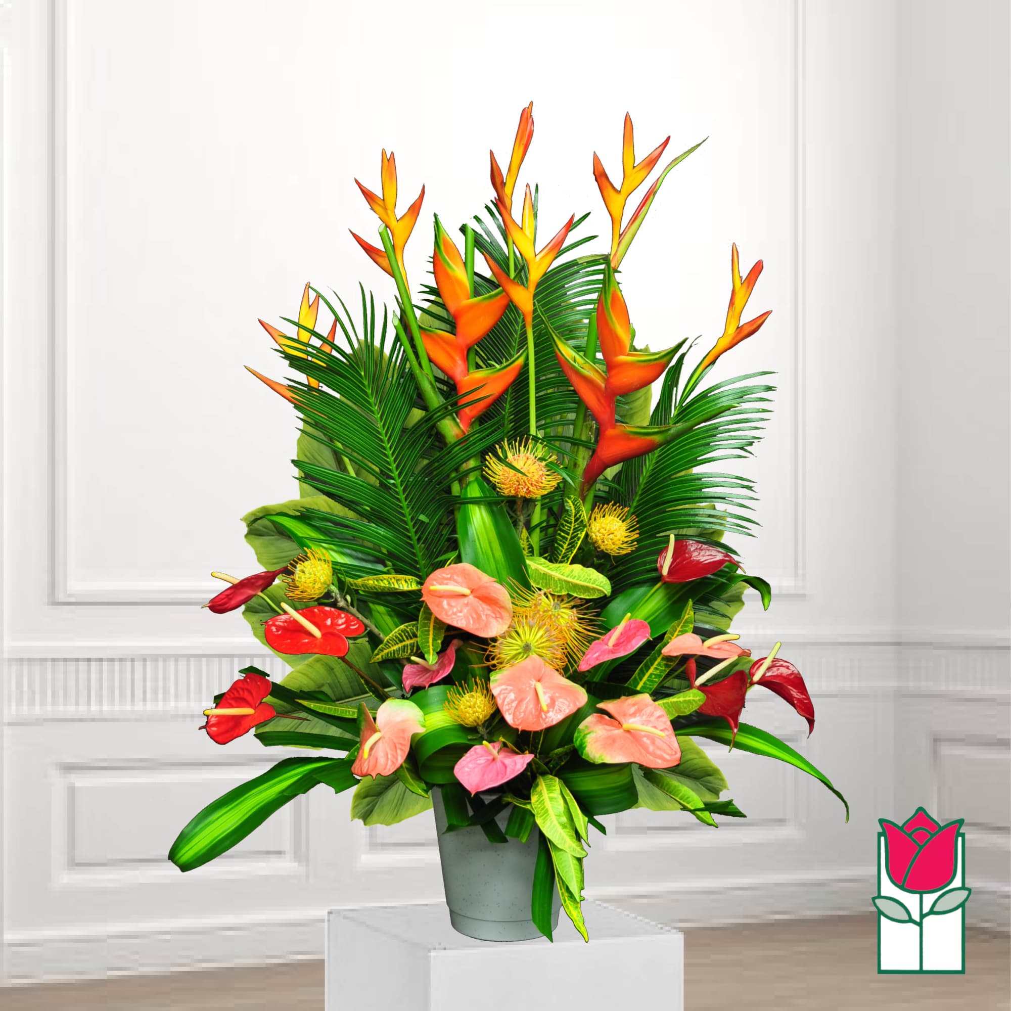 Tropical arrangement with orange heliconia and red anthuriums in a gray pot