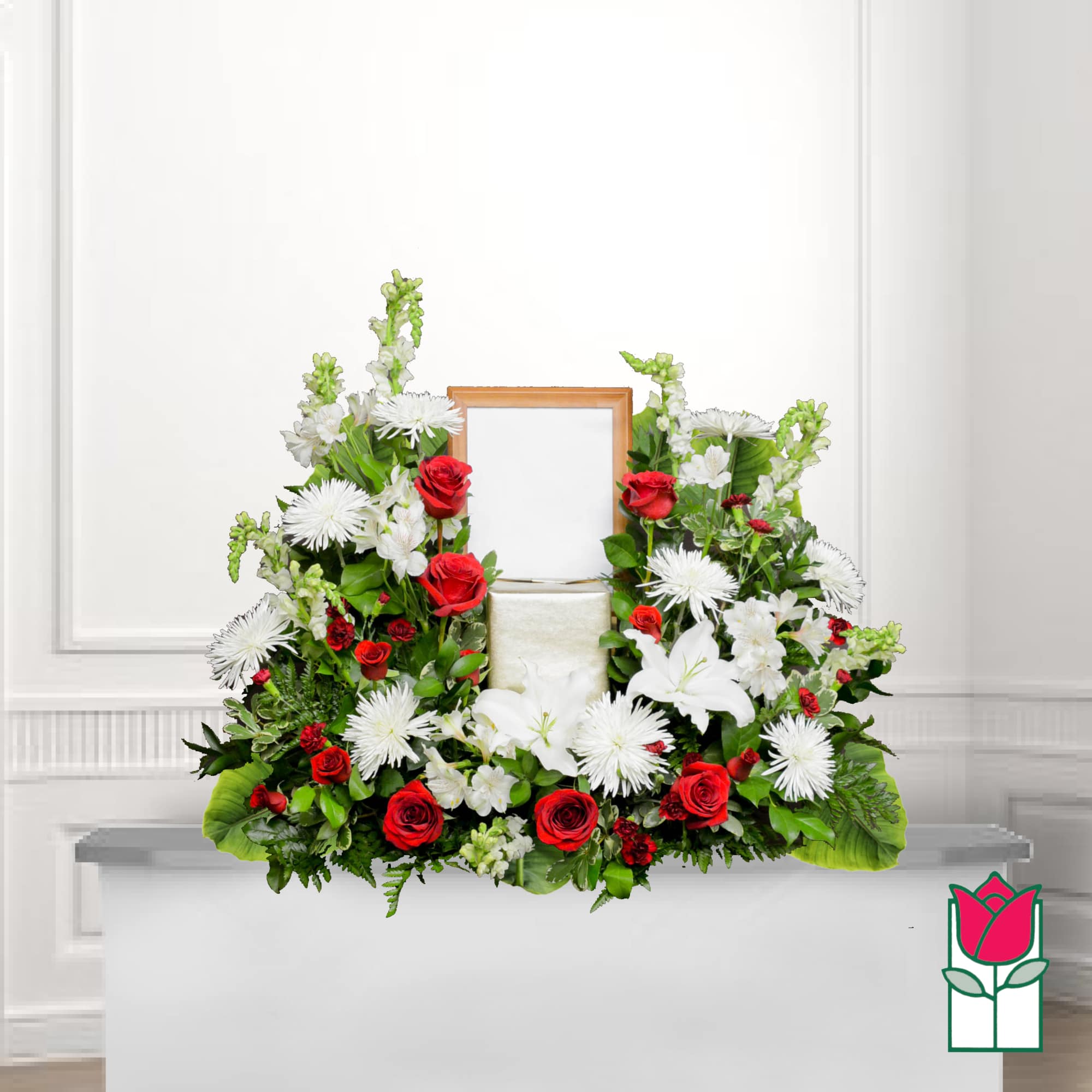 Sympathy floral arrangement with red roses and white lilies around a framed center