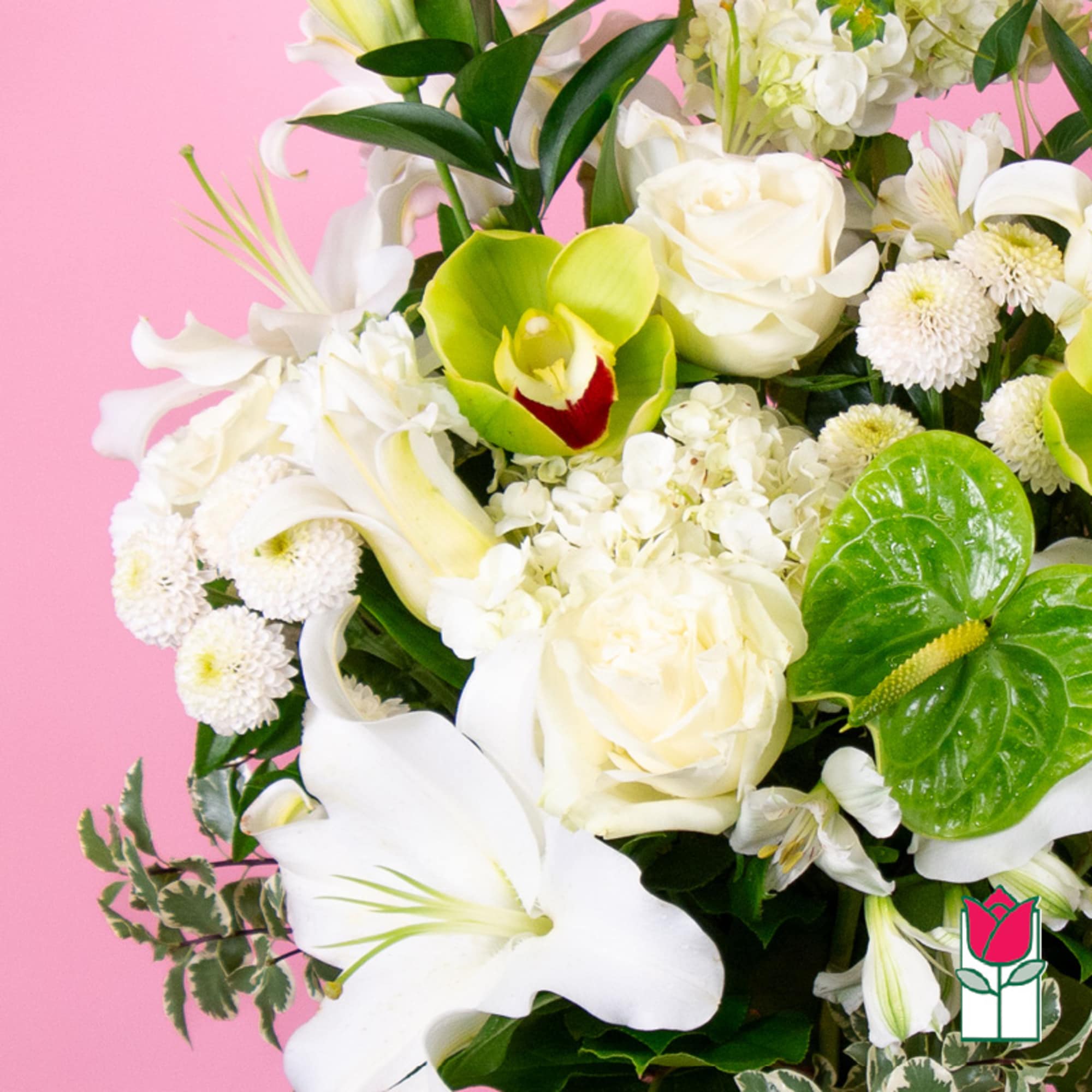 White lilies, roses, and green orchids in a bouquet against a pink background.