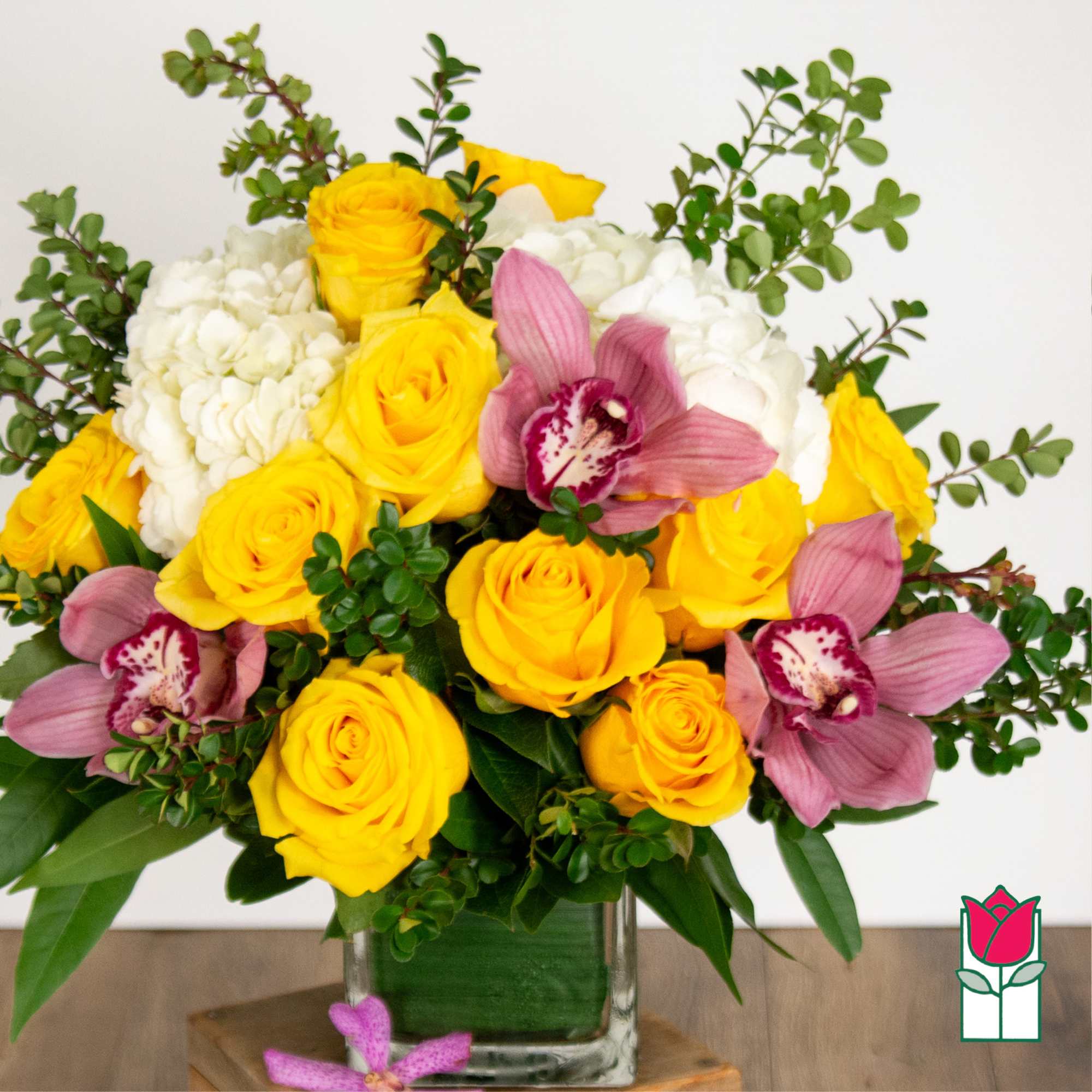 Yellow roses and pink orchids in a glass vase