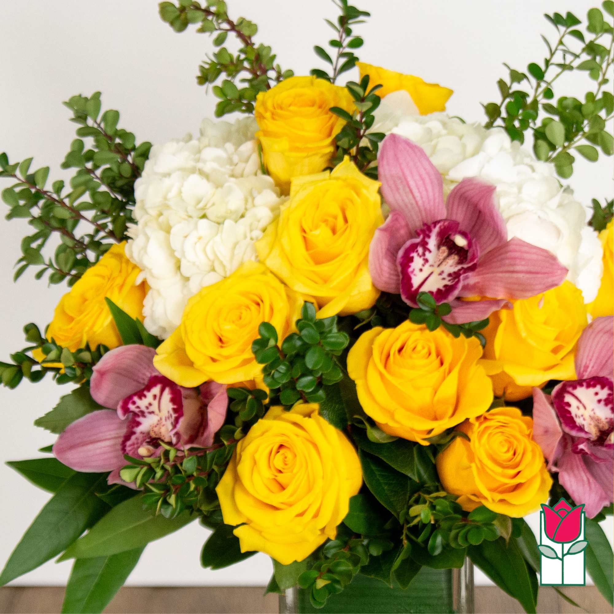 Bouquet of yellow roses, white hydrangeas, and pink orchids in a vase