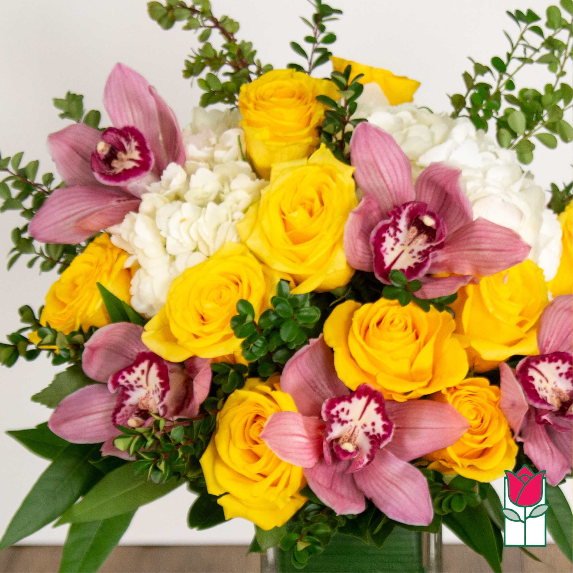 Bouquet of yellow roses, pink orchids, and white hydrangeas in a vase