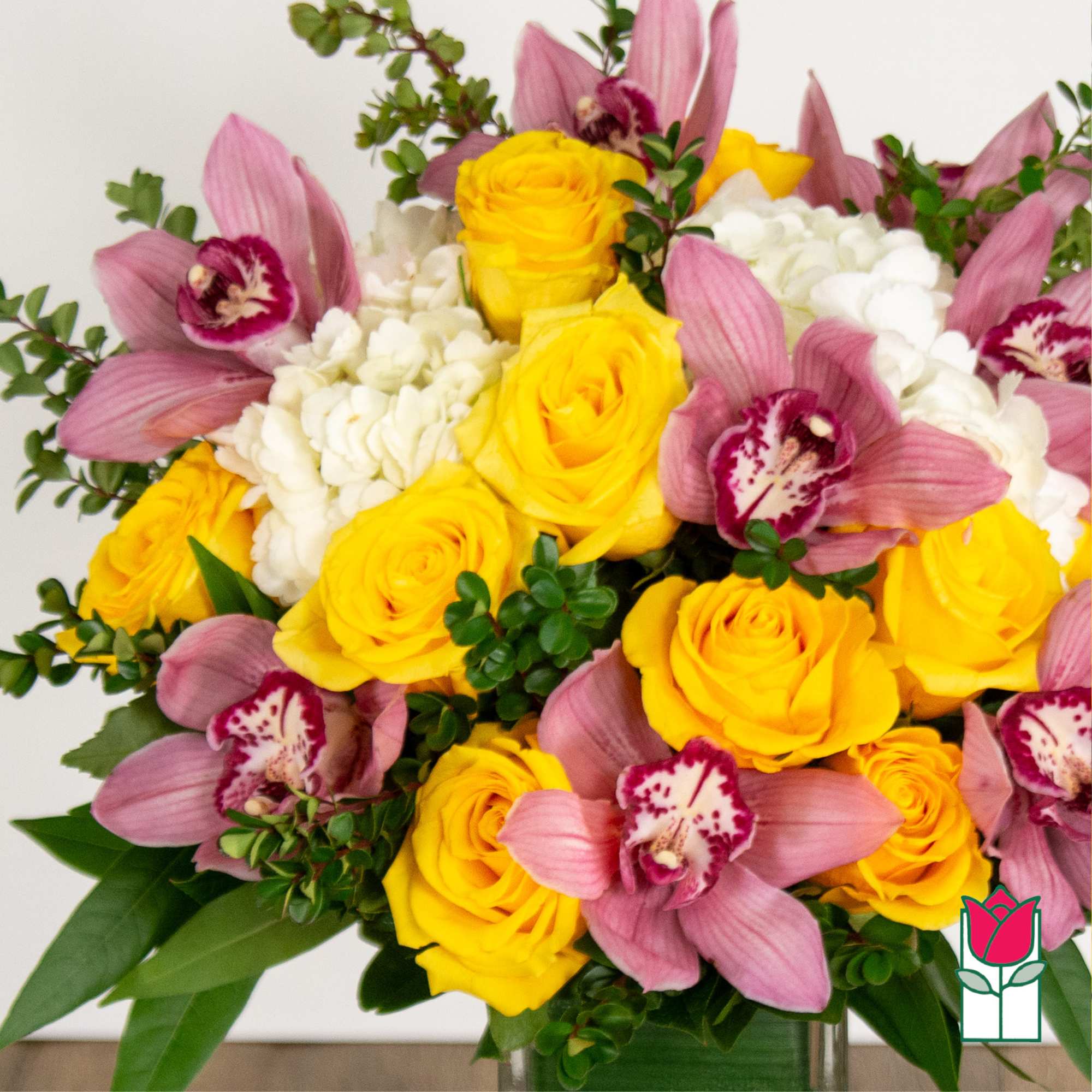 Bouquet of yellow roses, pink orchids, and white hydrangeas in a vase