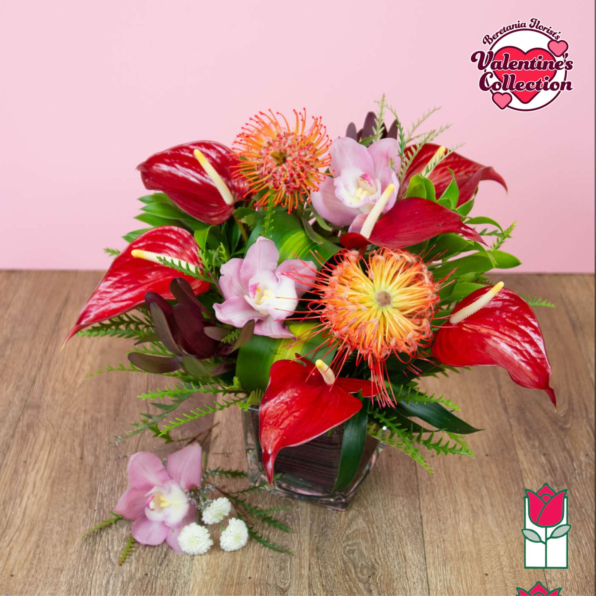 Red anthuriums and pink orchids arranged in a glass vase