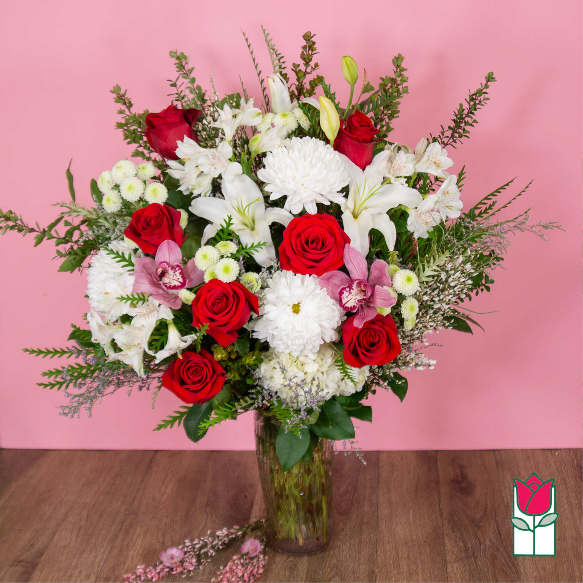 Bouquet of red roses, white lilies, and pink orchids in a glass vase