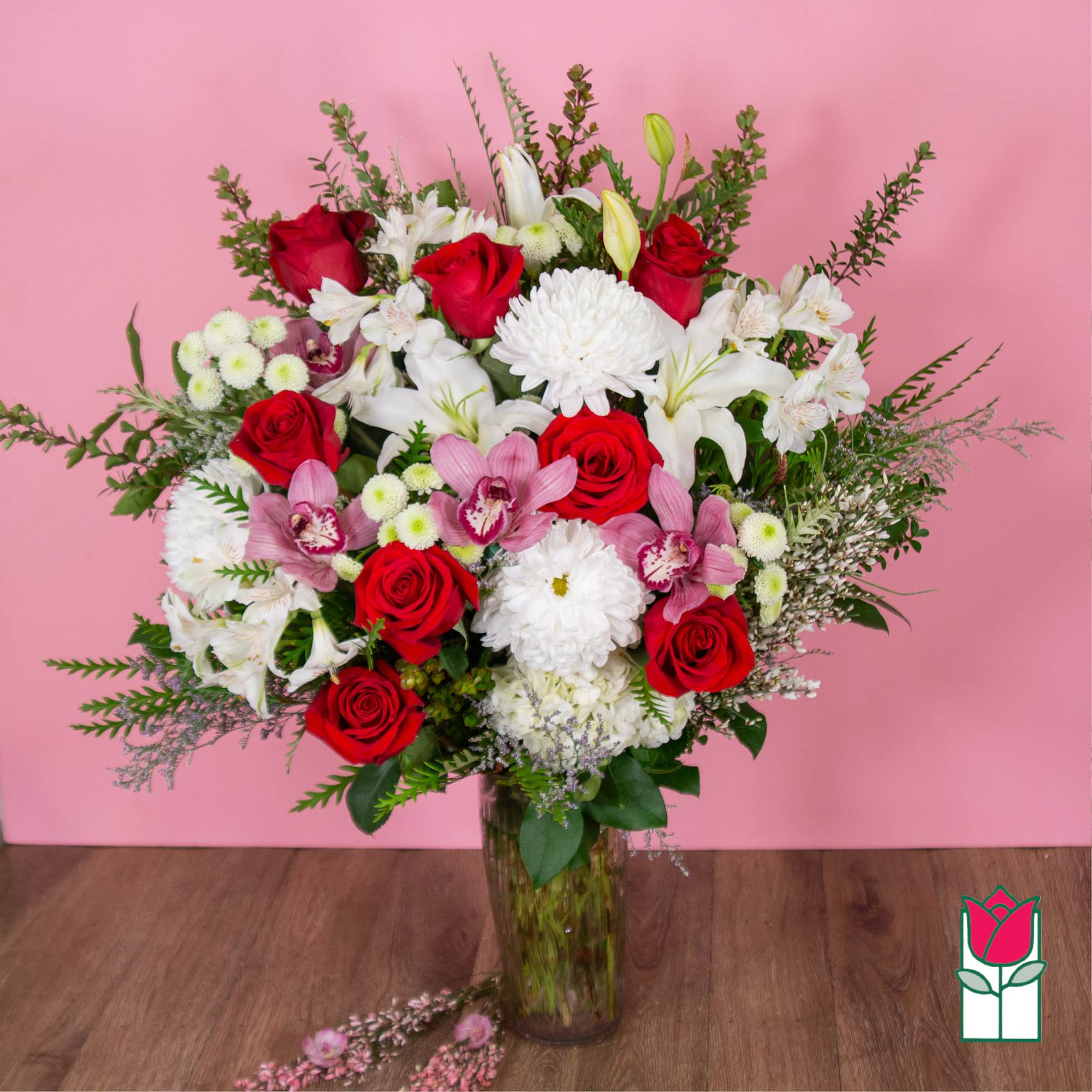 Bouquet of red roses, white lilies, and pink orchids in a glass vase