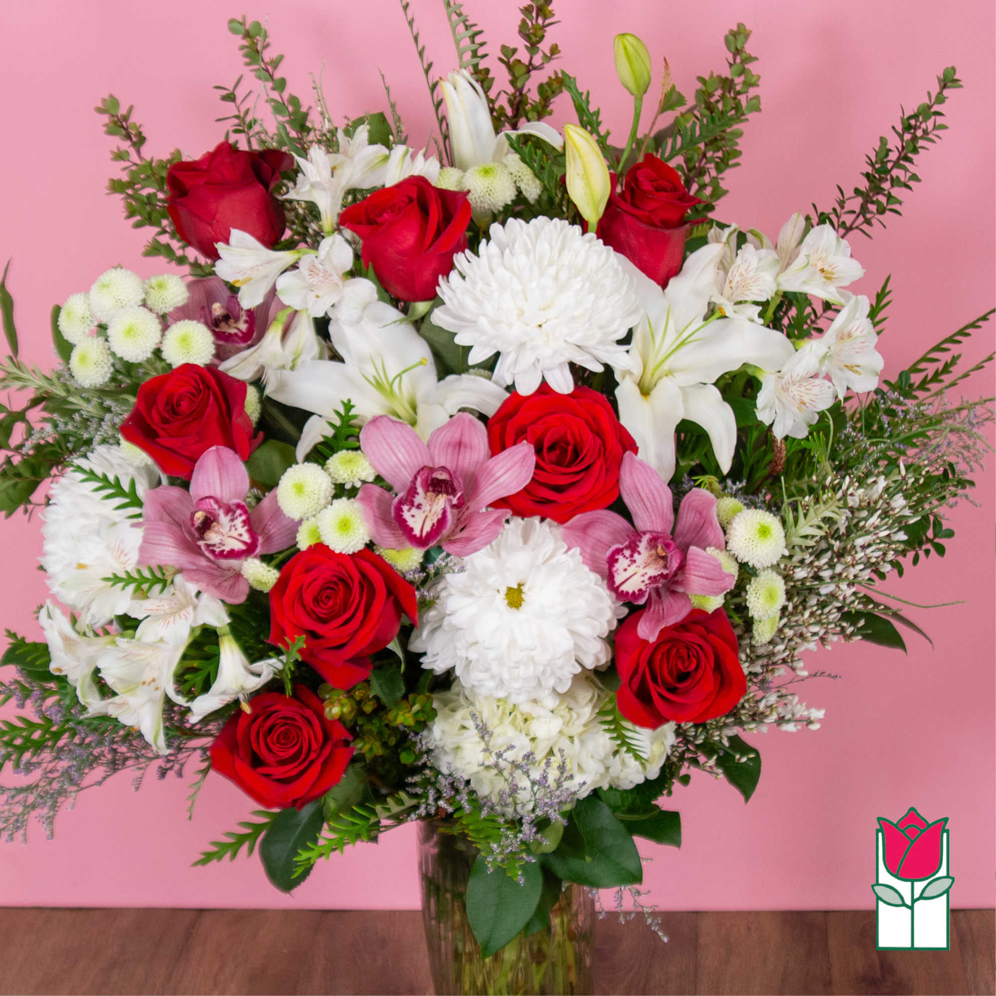 Bouquet of red roses, white lilies, and pink orchids in a glass vase