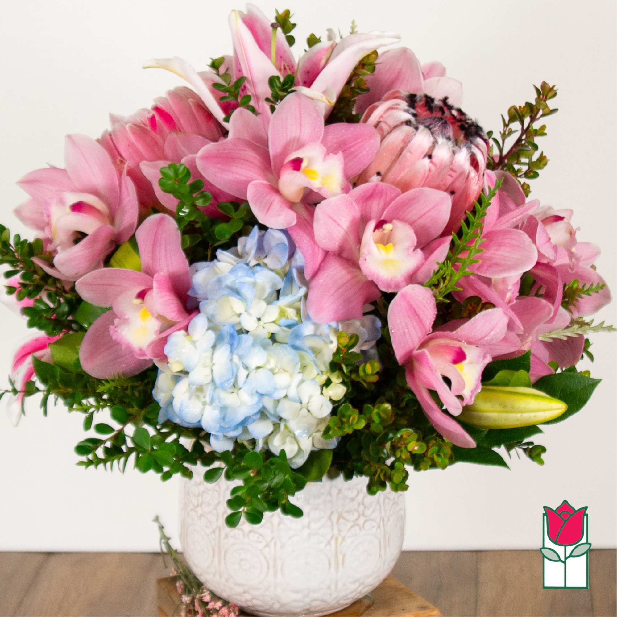 Pink orchids and blue hydrangea in a white vase
