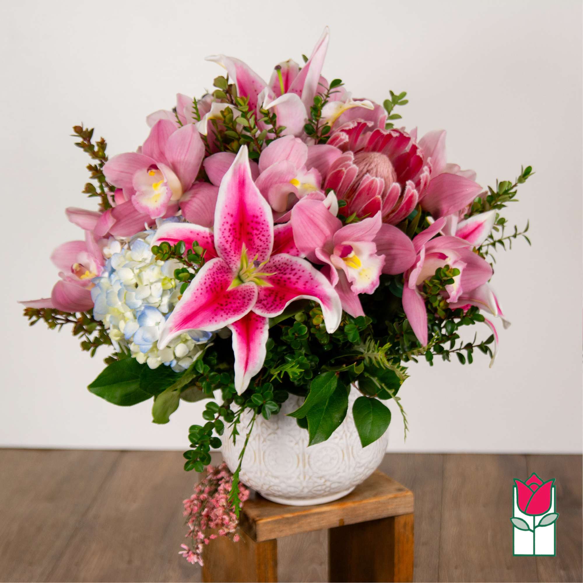 Pink lilies and orchids arranged in a white vase