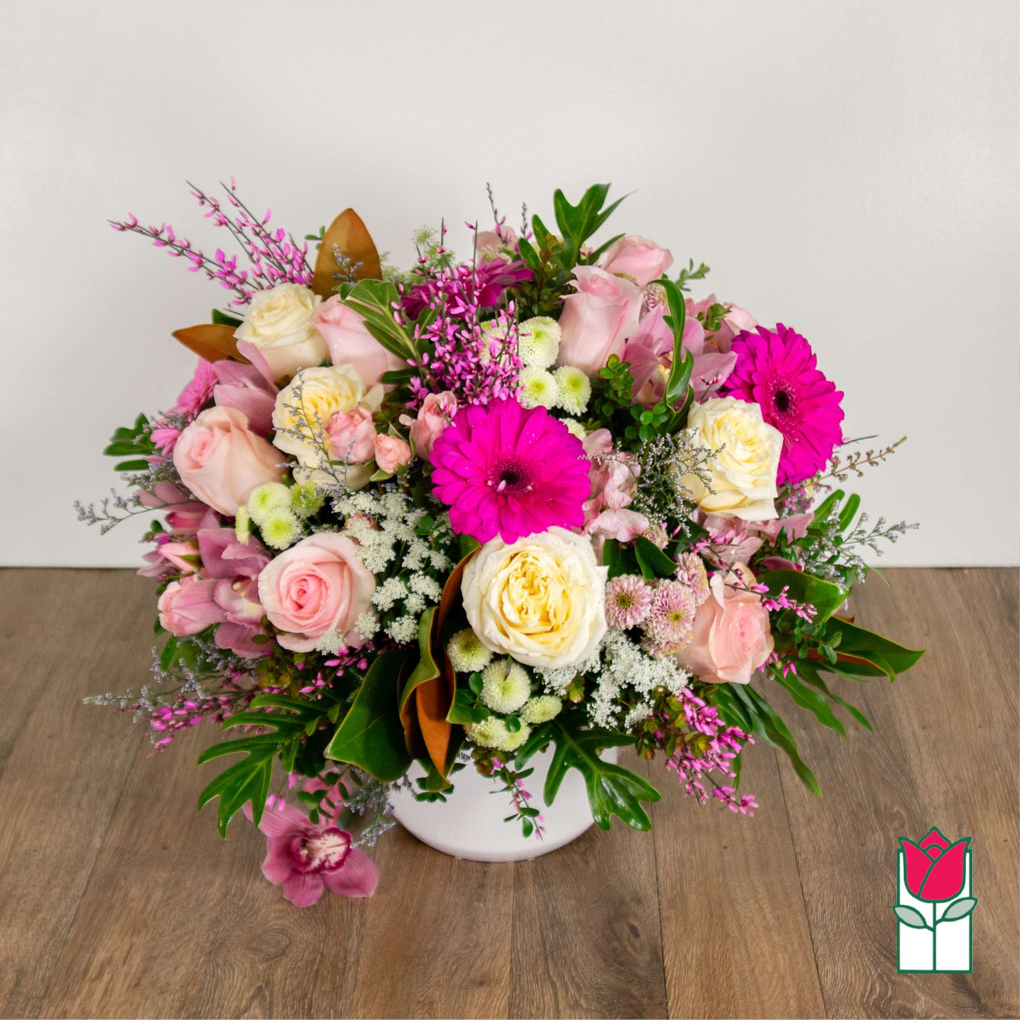 Pink and cream rose bouquet with bright magenta daisies in a white vase