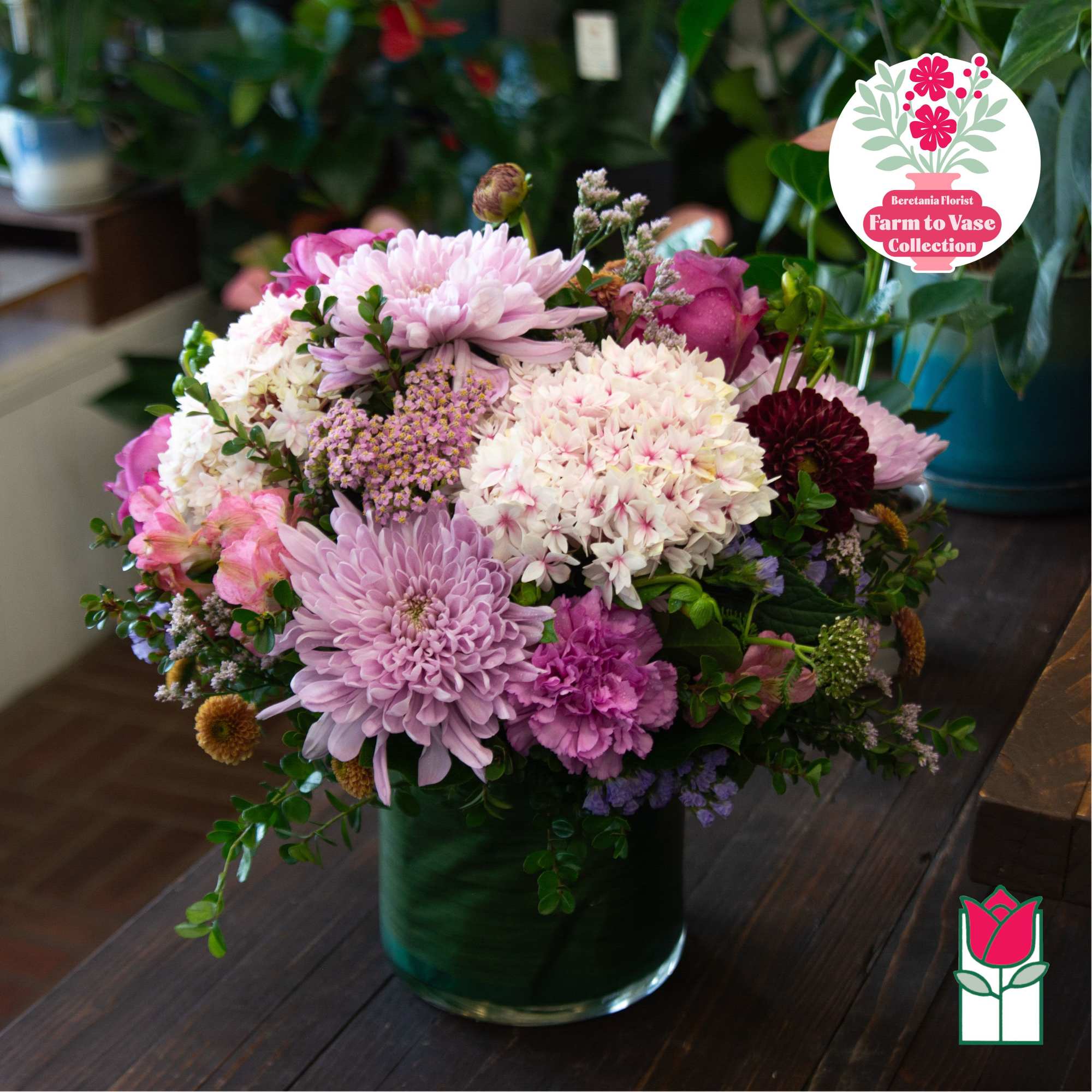 Pink and white mixed flower arrangement in a green glass vase