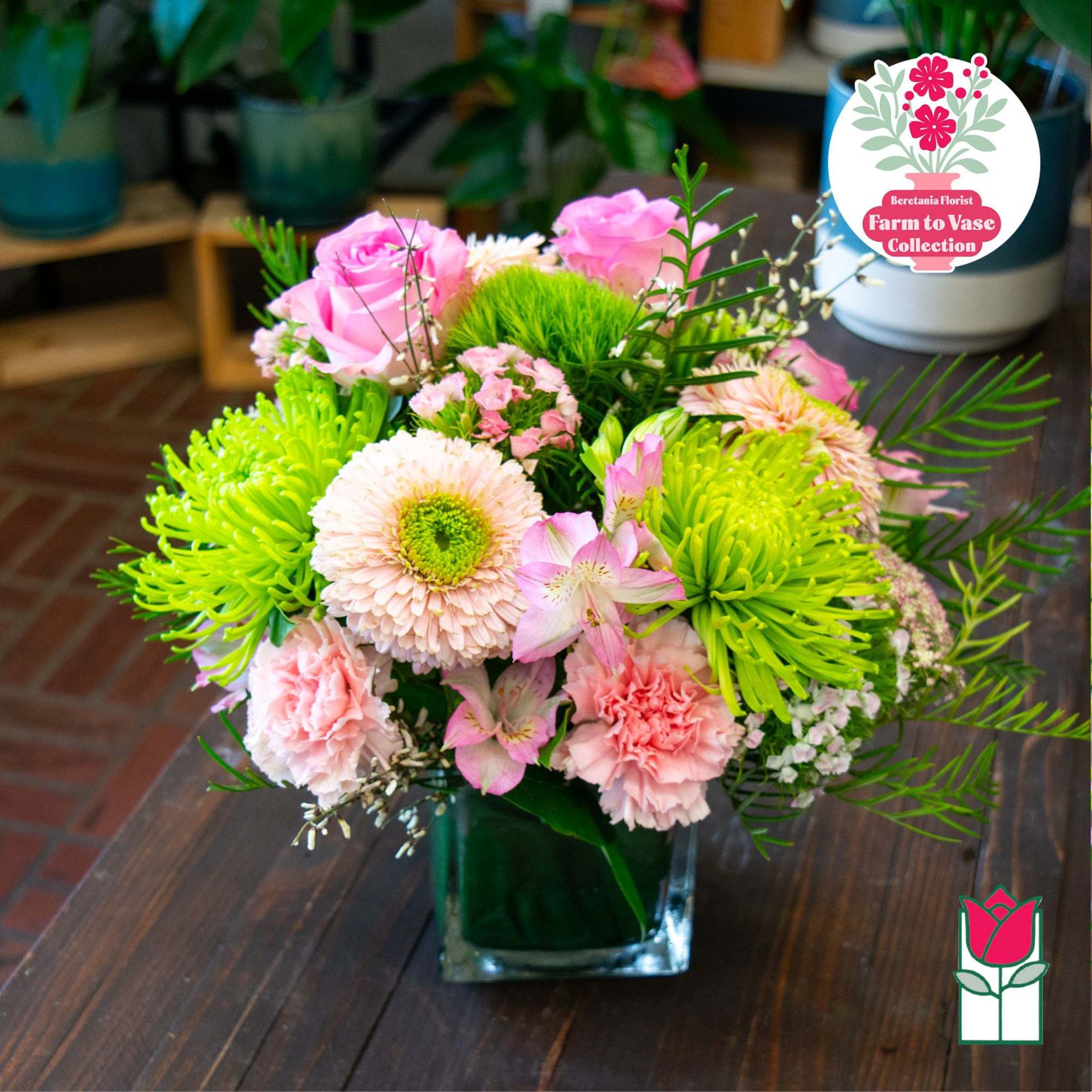 Pink and green mixed flower arrangement in a square glass vase