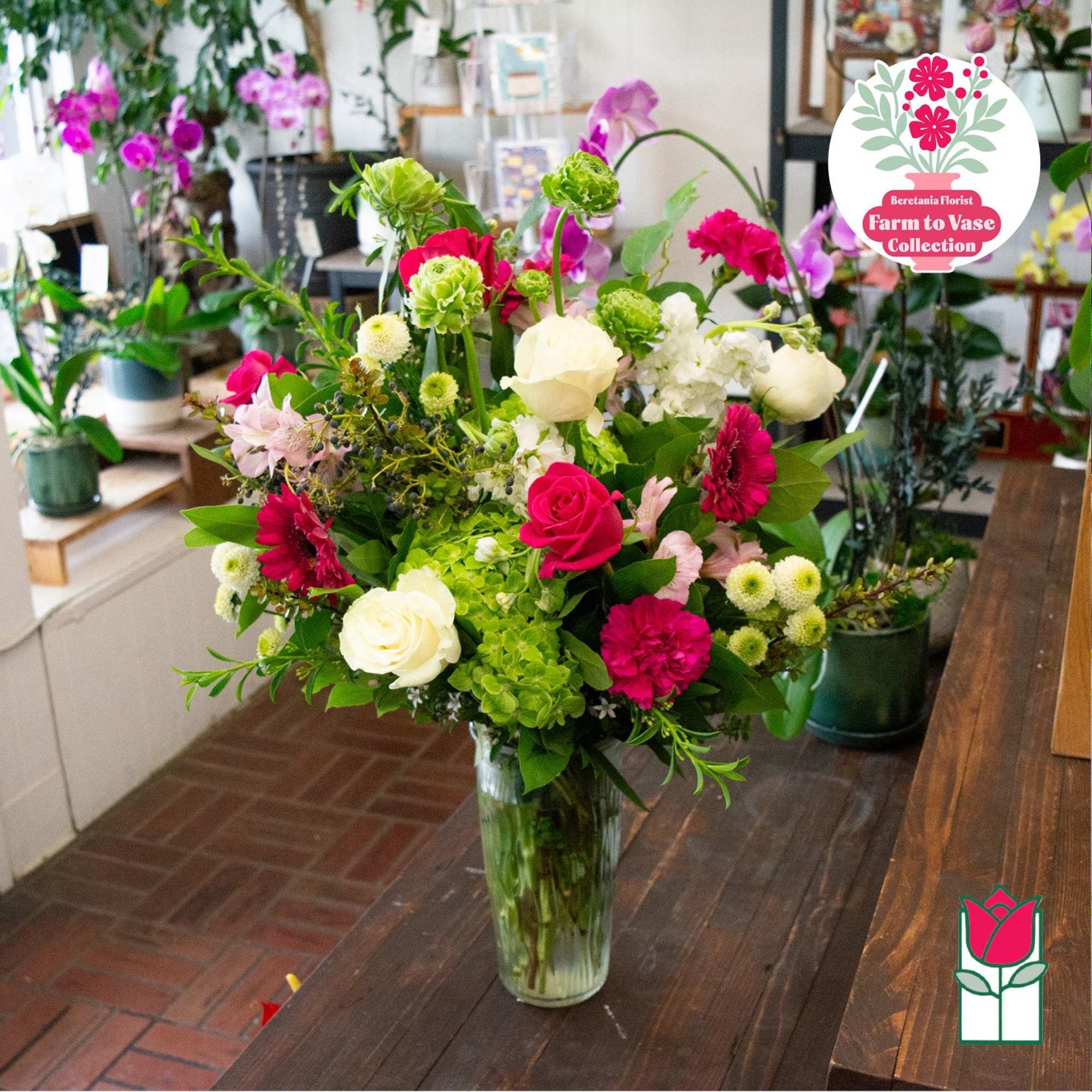 Mixed bouquet of pink, white, and green flowers in a clear glass vase