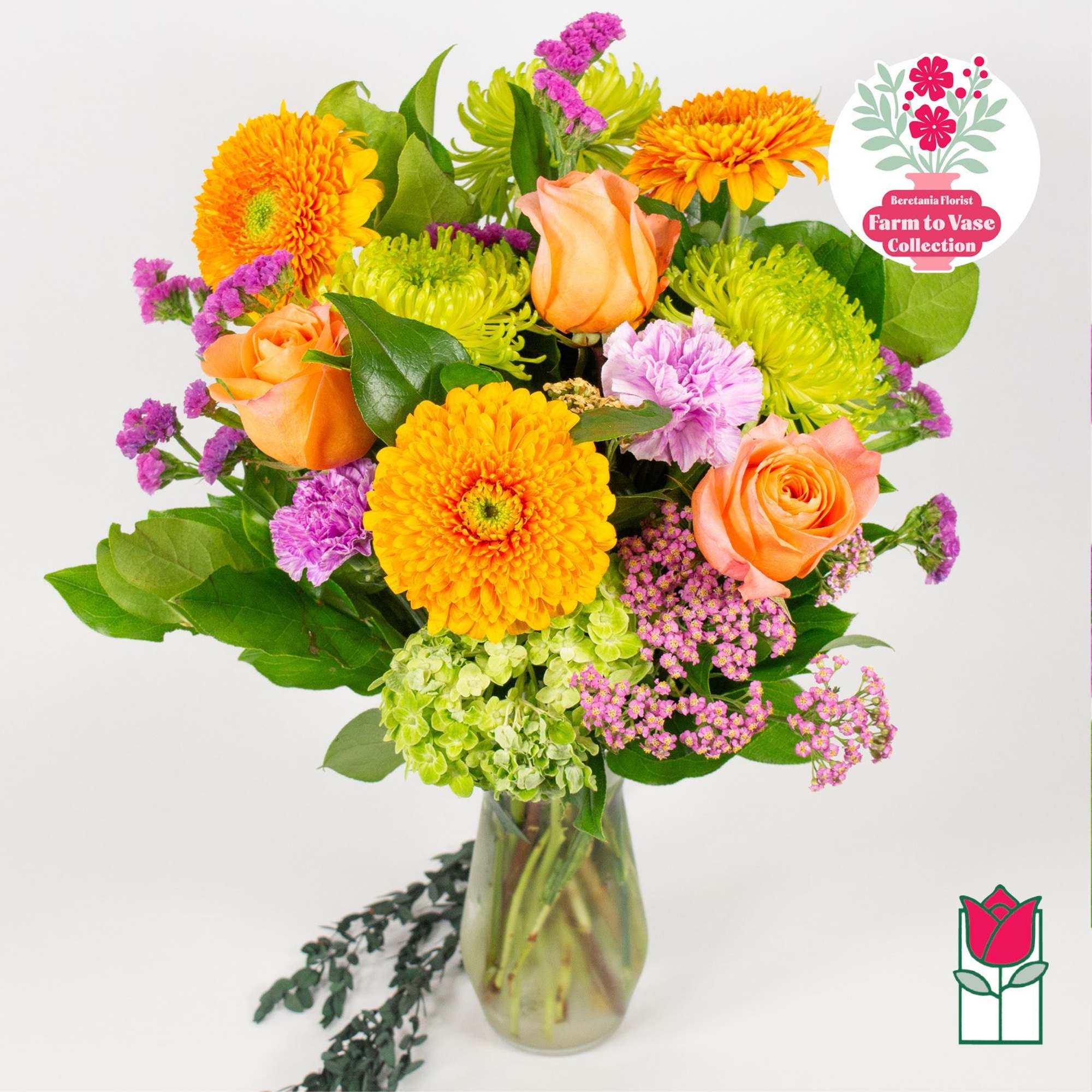 Bouquet of orange roses, yellow gerberas, and purple filler in a glass vase