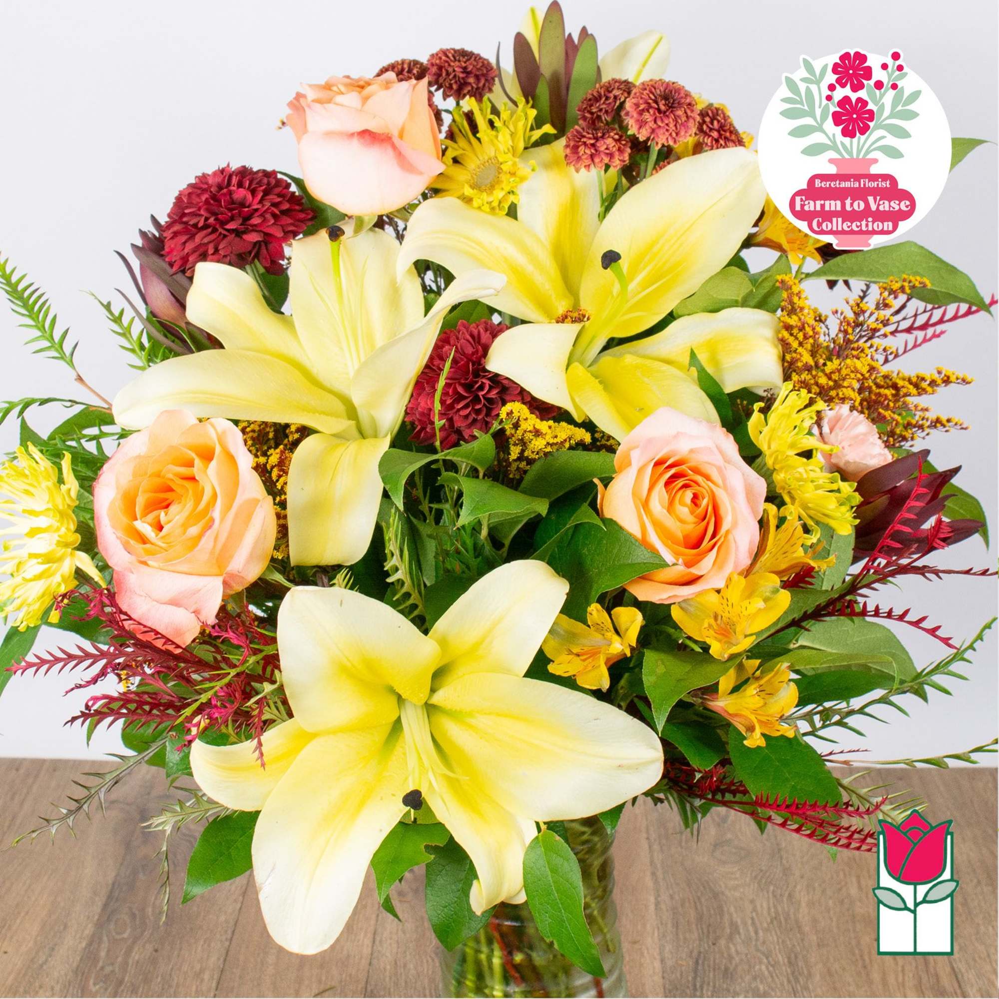 Bouquet of yellow lilies and peach roses in a glass vase