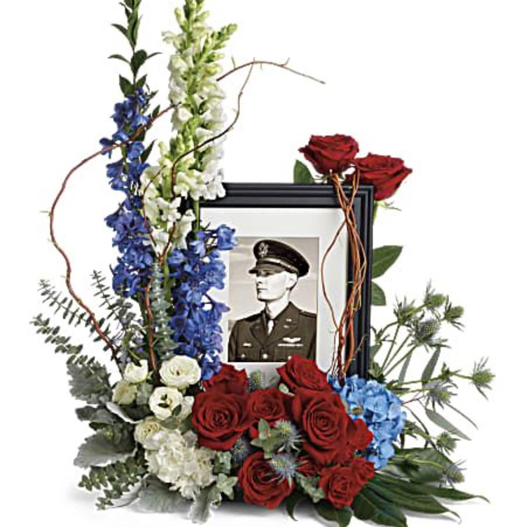 Patriotic red, white, and blue floral memorial framing a black photo frame with military portrait.