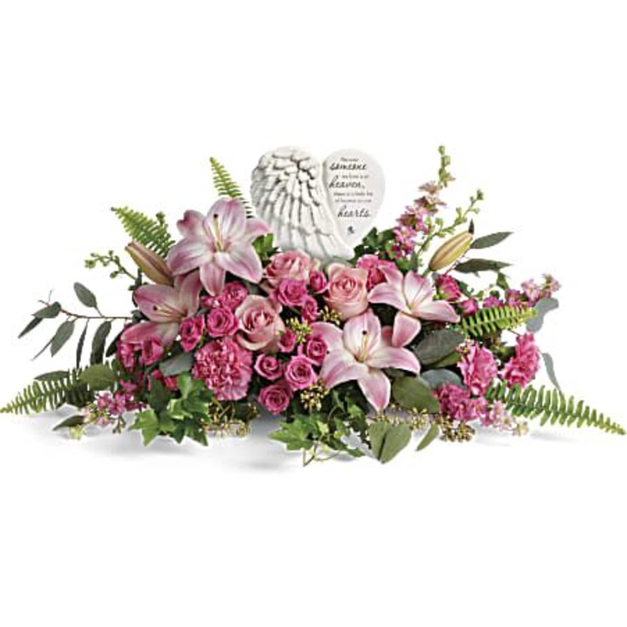 Pink lily and rose sympathy arrangement with angel-wing memorial stone in a low horizontal design.
