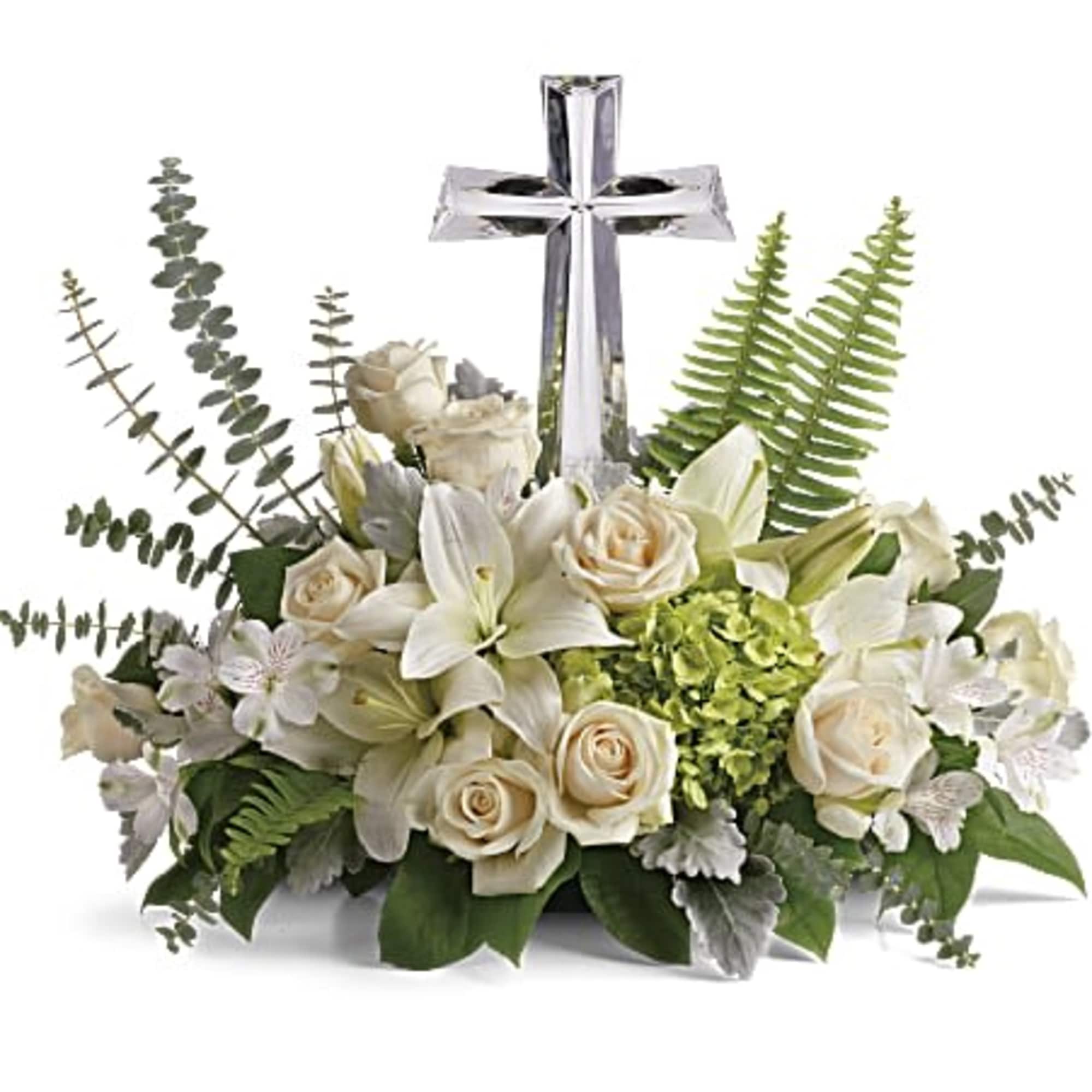 Low white and green floral arrangement with roses, lilies, and a clear cross figurine in the center