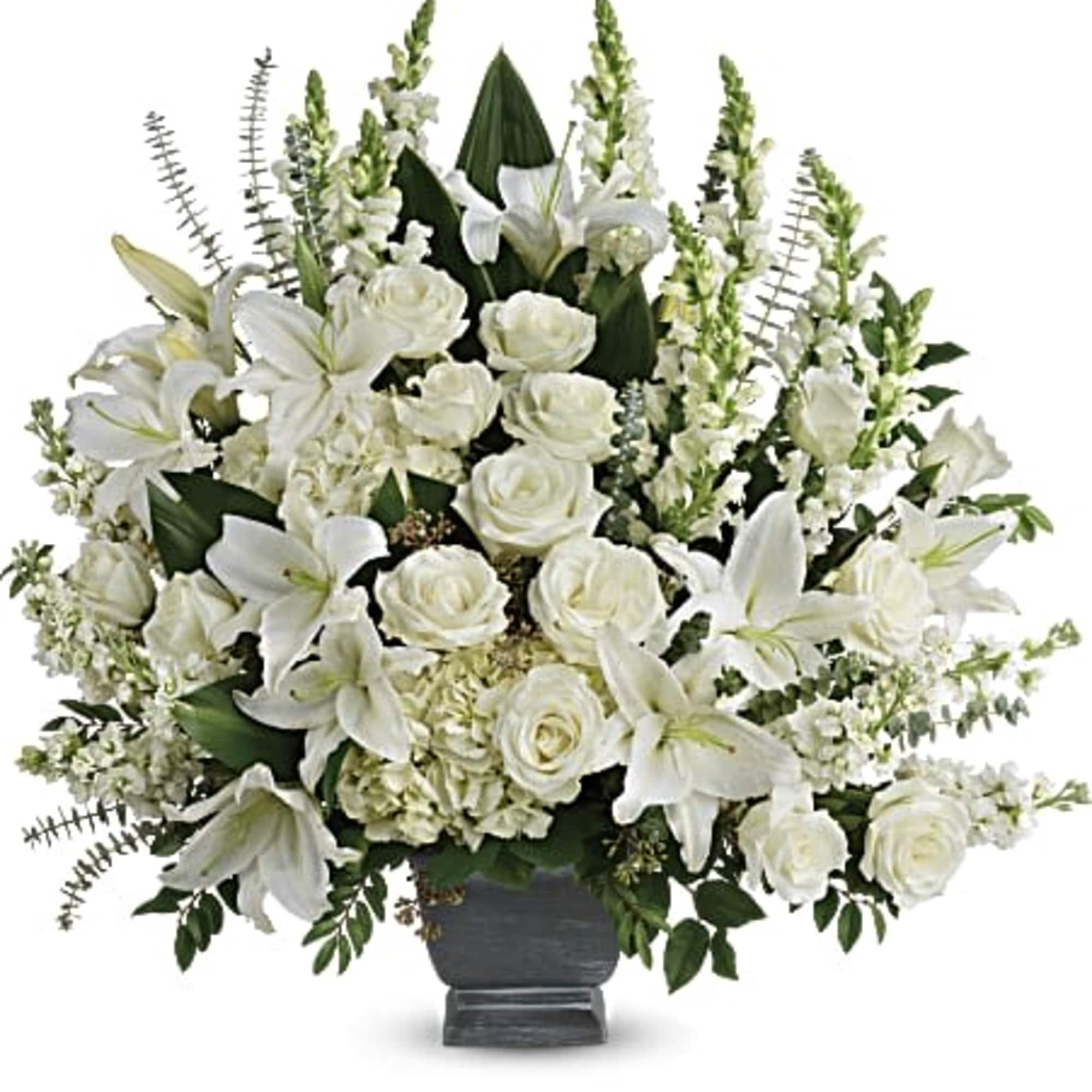Large all-white arrangement of lilies, roses, and hydrangeas in a dark pedestal vase