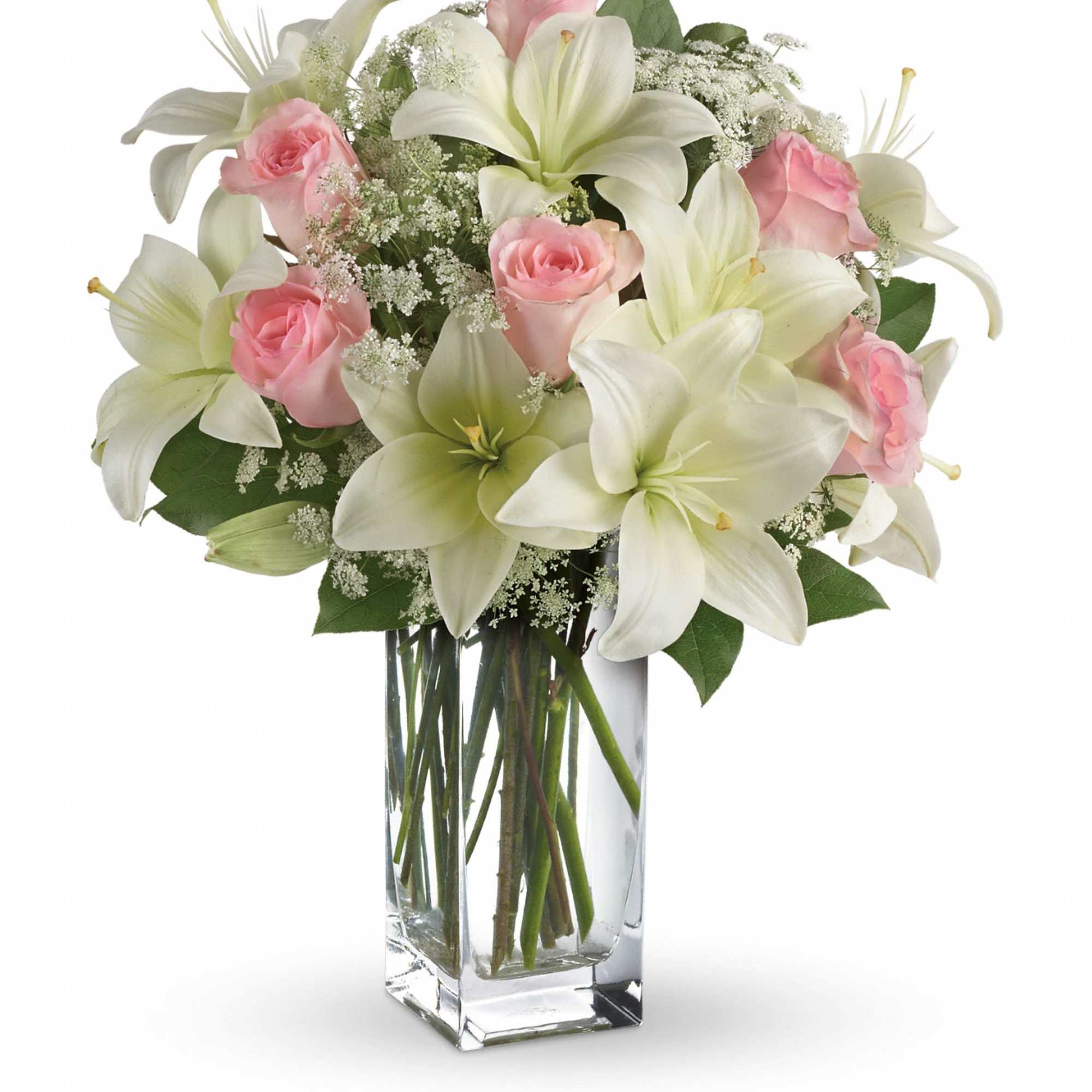Arrangement of white lilies and pink roses with white filler flowers in a tall clear glass vase