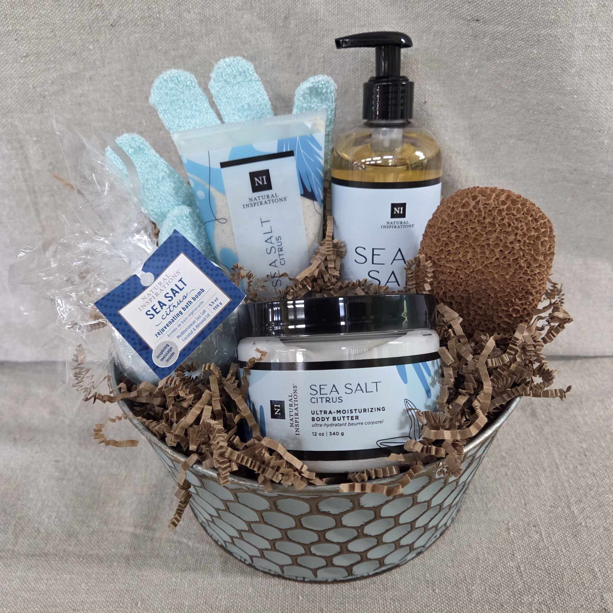 Sea salt citrus spa gift basket with lotions, soaps, gloves, and sponge in a metal container.