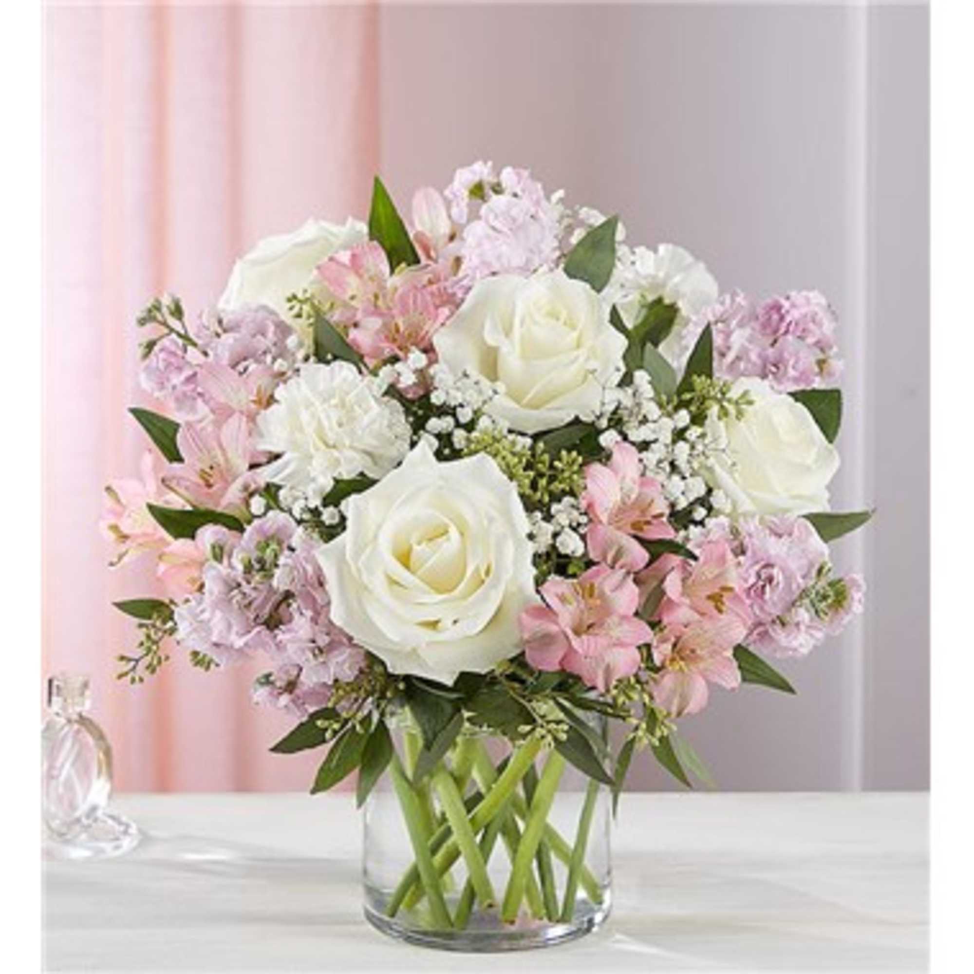 Pink and white bouquet of roses and lilies in a clear glass vase
