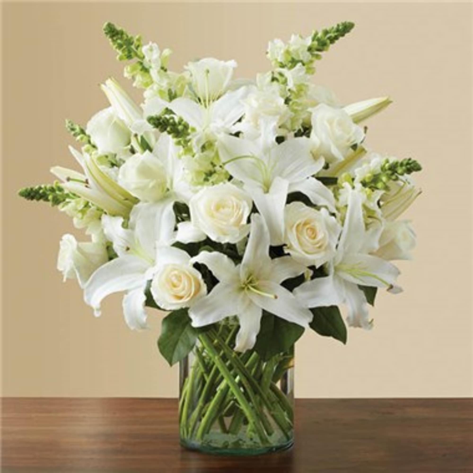 White lilies and roses arranged in a clear glass vase