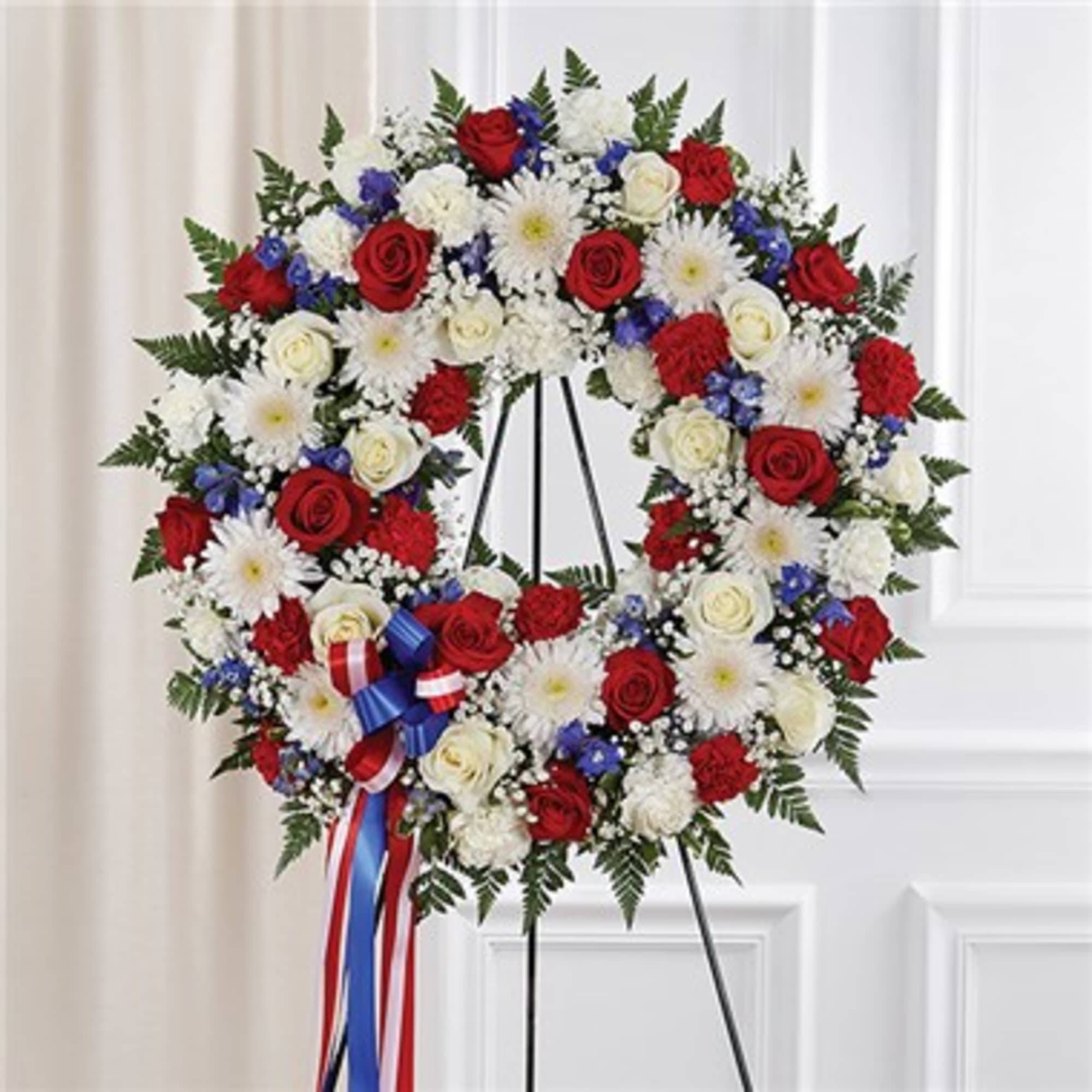 Circular floral wreath of red, white, and blue flowers on a stand