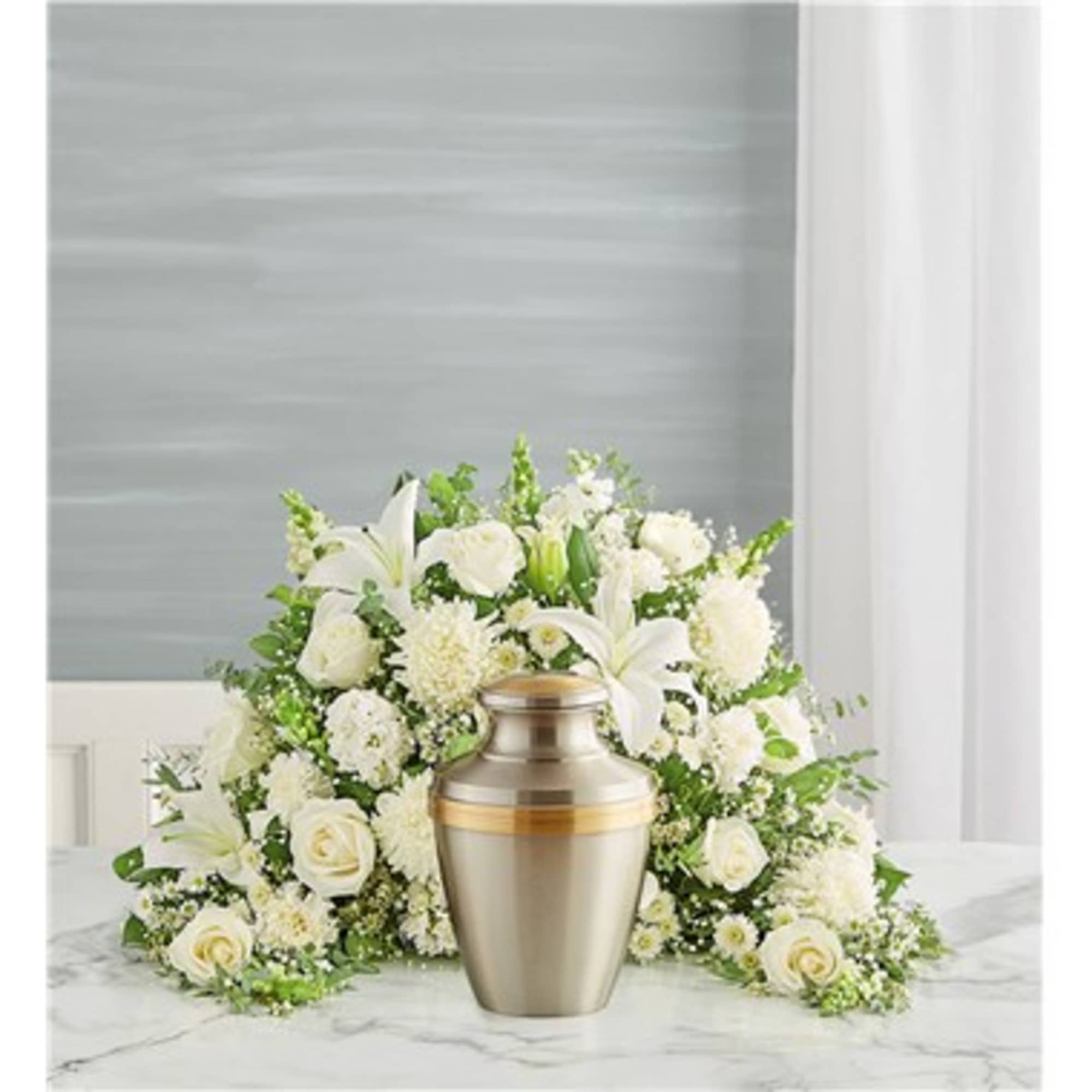White floral funeral arrangement with an urn in front