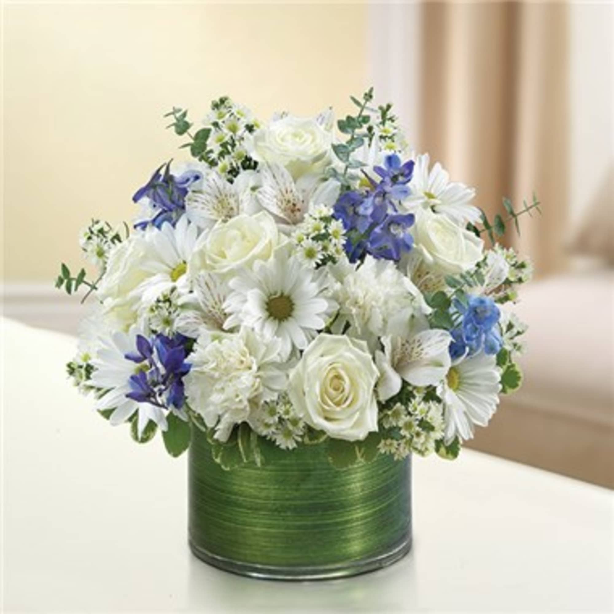 White and blue mixed bouquet in a green cylindrical vase
