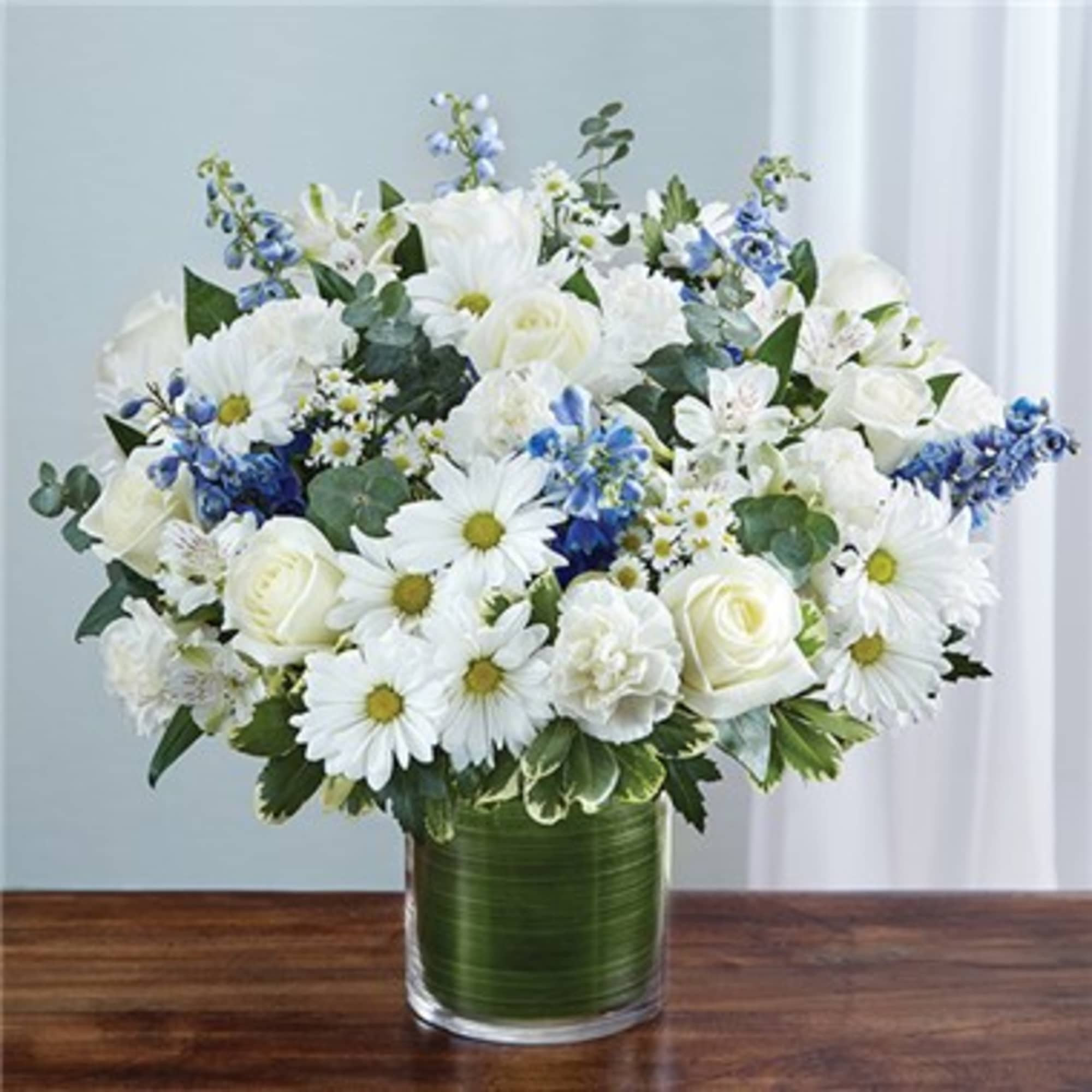 White flowers and blue accents arranged in a glass vase