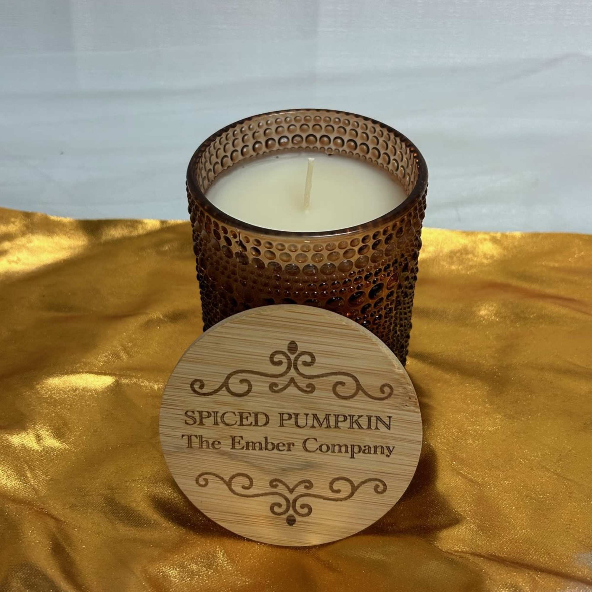 Spiced pumpkin candle in a textured glass jar with a wooden lid