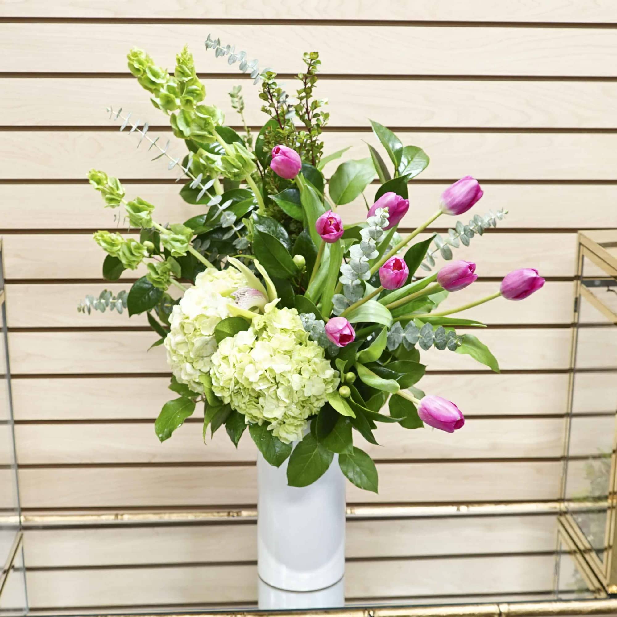 Pink tulips and pale green hydrangeas in a white vase