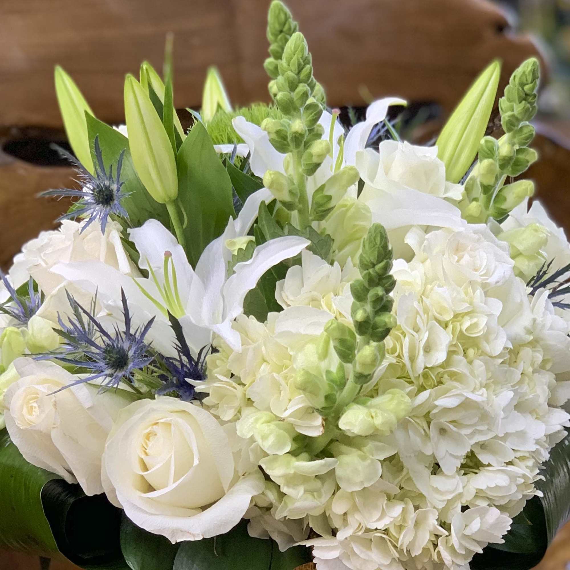 White roses, lilies, hydrangea, and green snapdragons in a bouquet