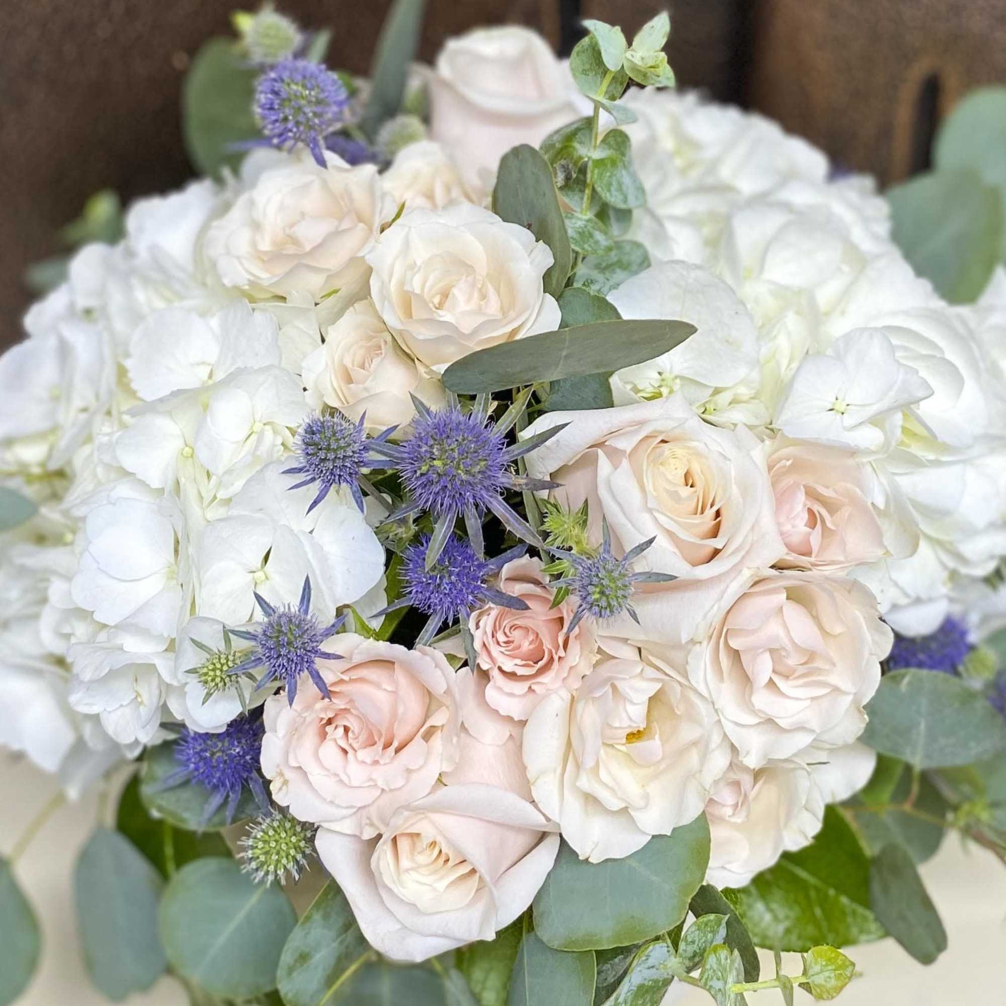 Bouquet of pale pink roses, white hydrangeas, and purple thistle-like flowers