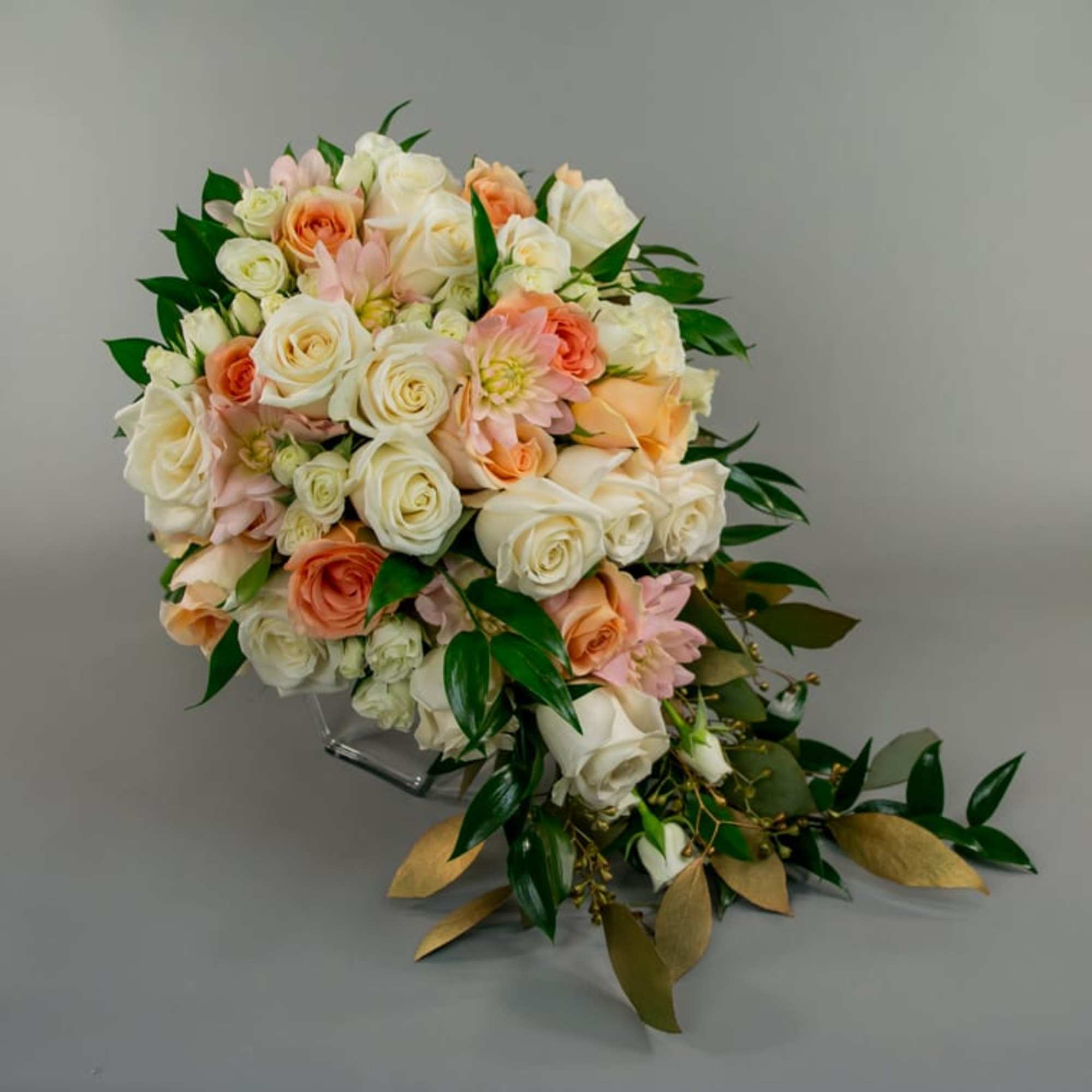 Bouquet of cream, peach, and pink roses with greenery