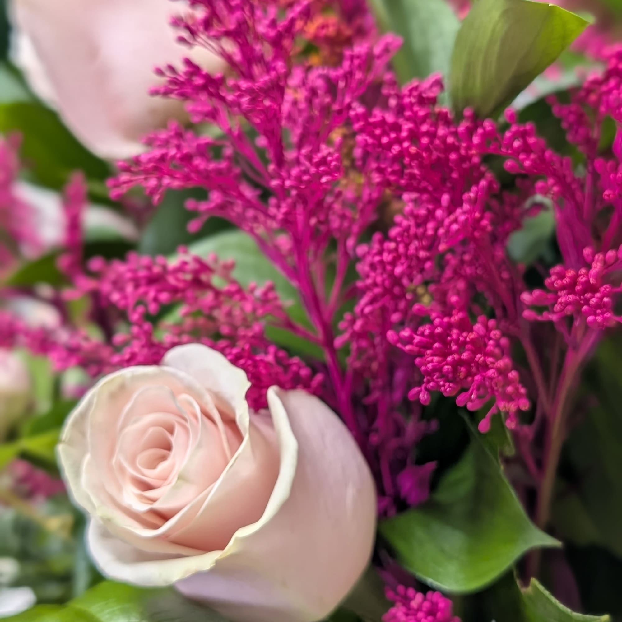 Close-up bouquet with pale pink roses and bright magenta filler flowers
