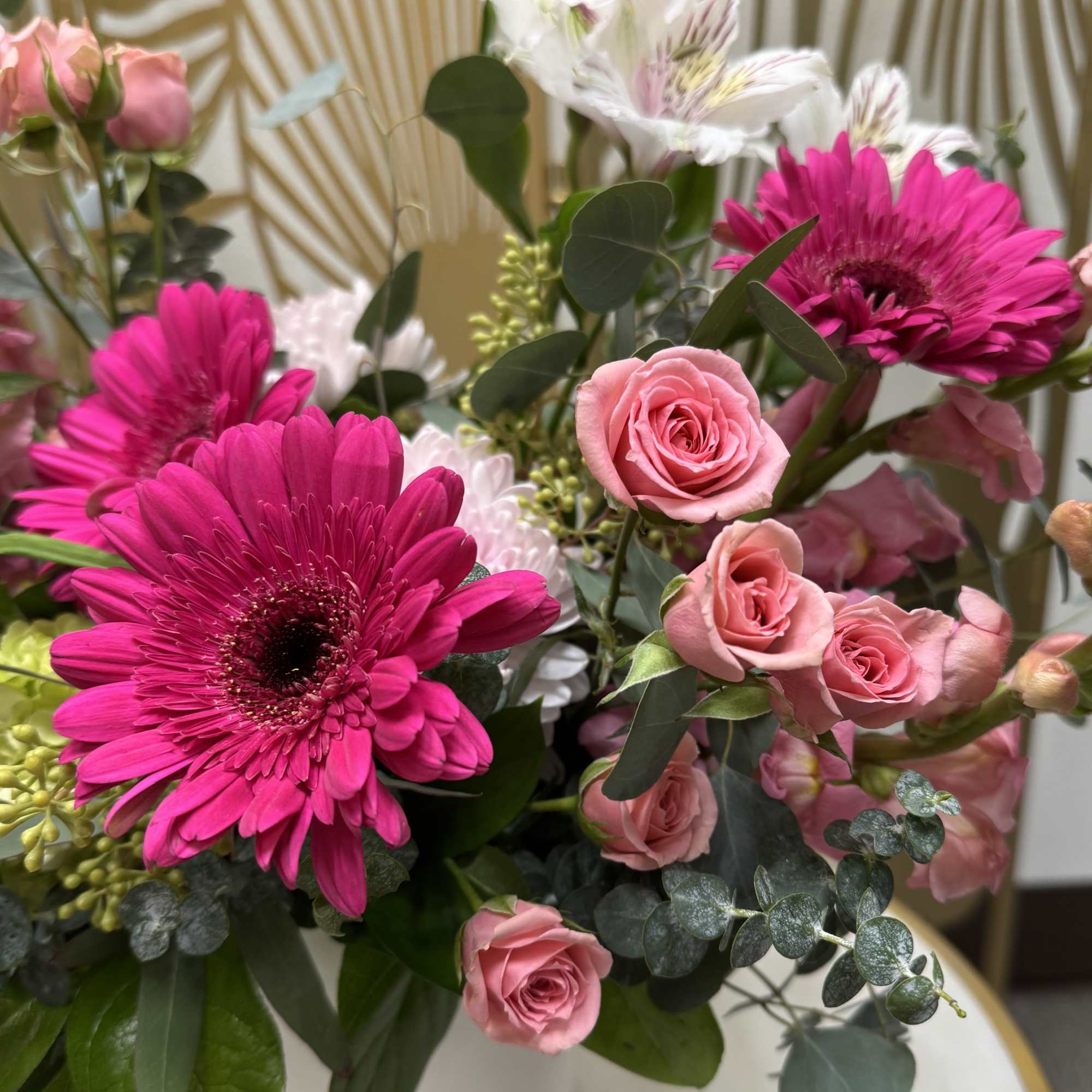 Pink roses and magenta gerbera daisies in a white vase