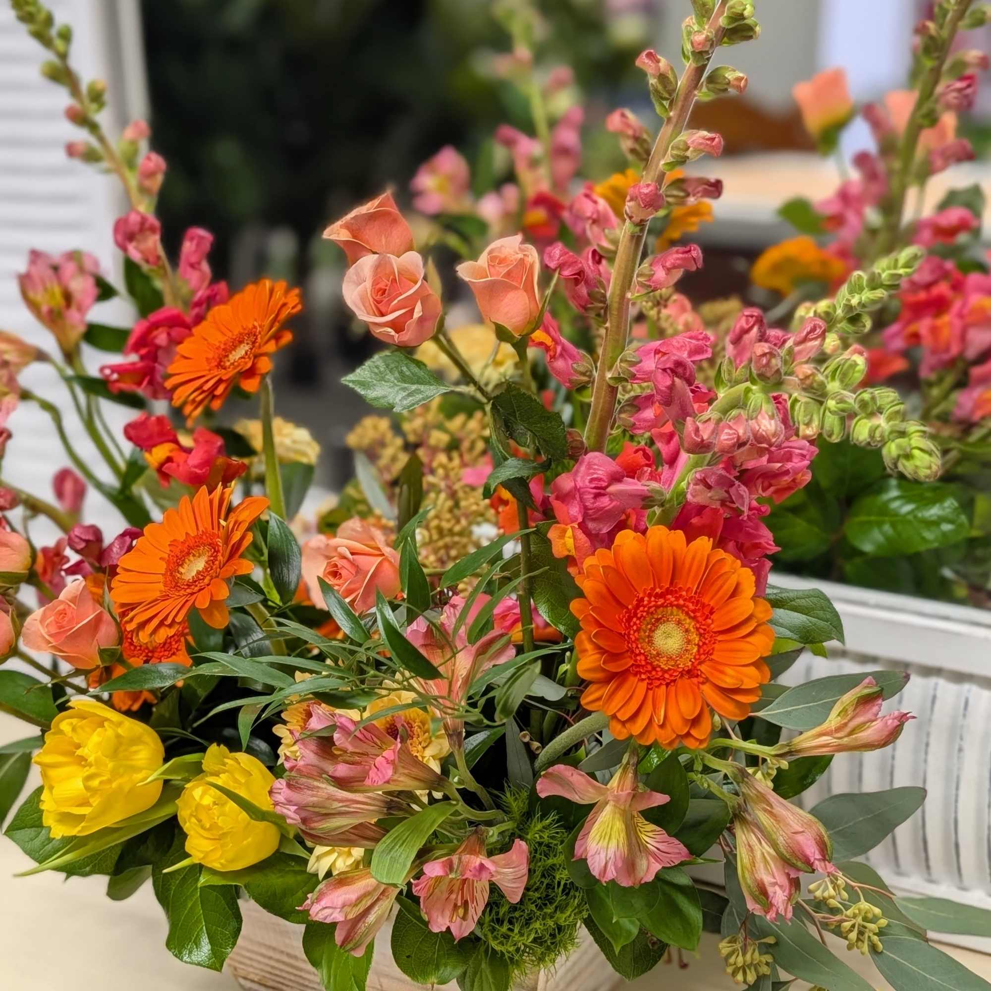 Mixed bouquet in a wooden box with orange gerberas, pink roses, and yellow blooms