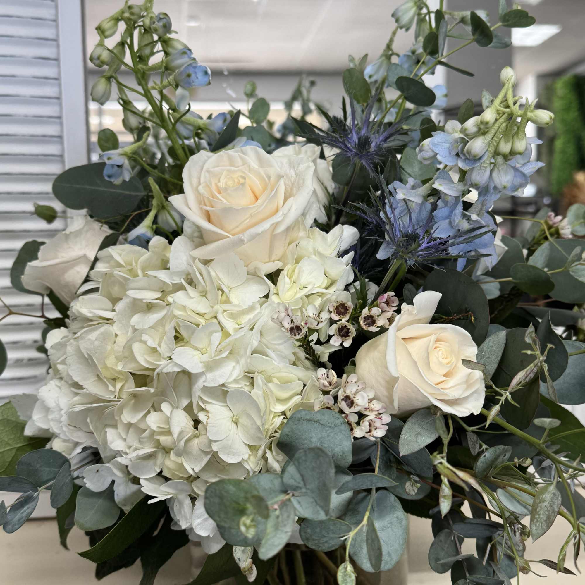 White roses and hydrangea bouquet with blue flowers and eucalyptus