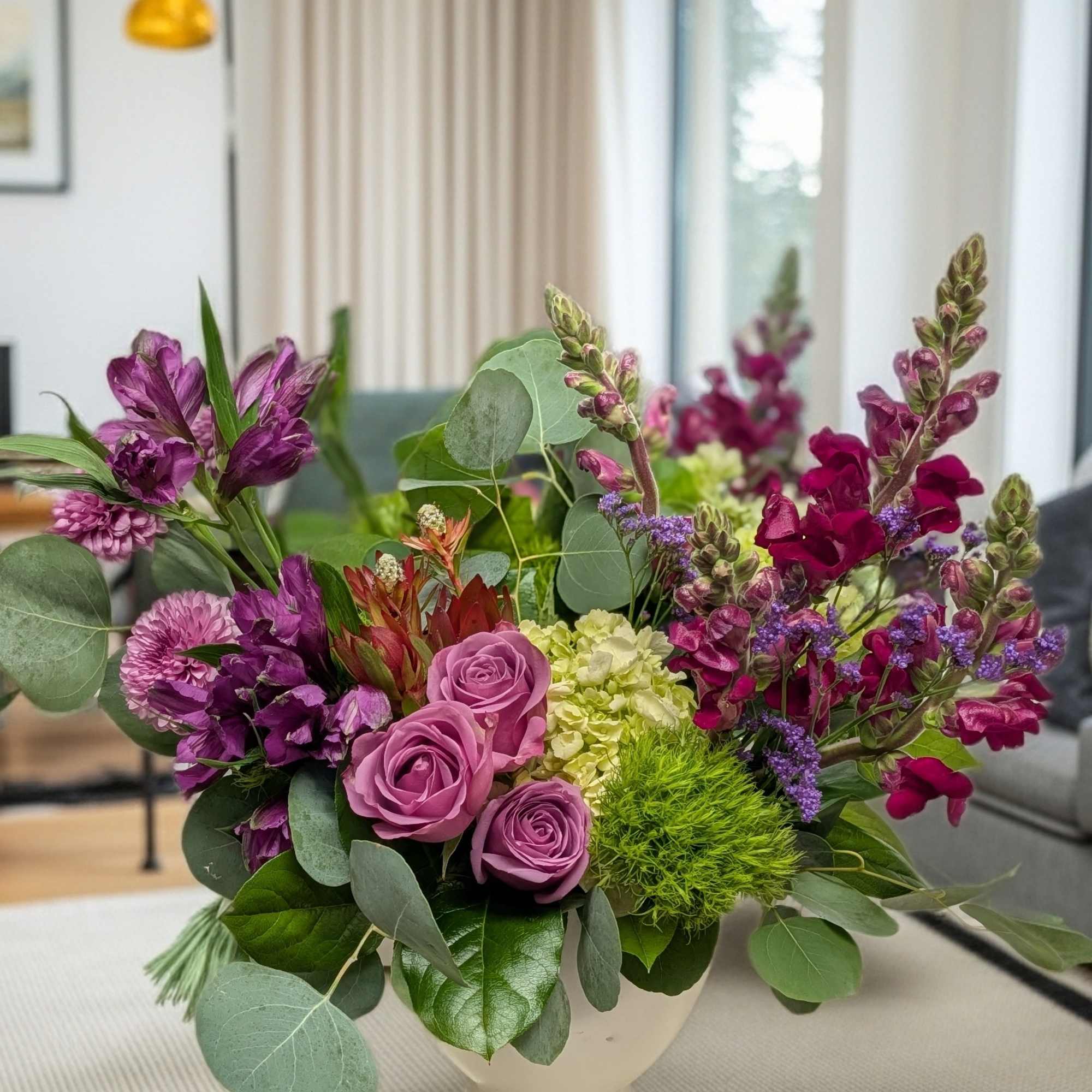 Purple and pink floral arrangement in a white vase
