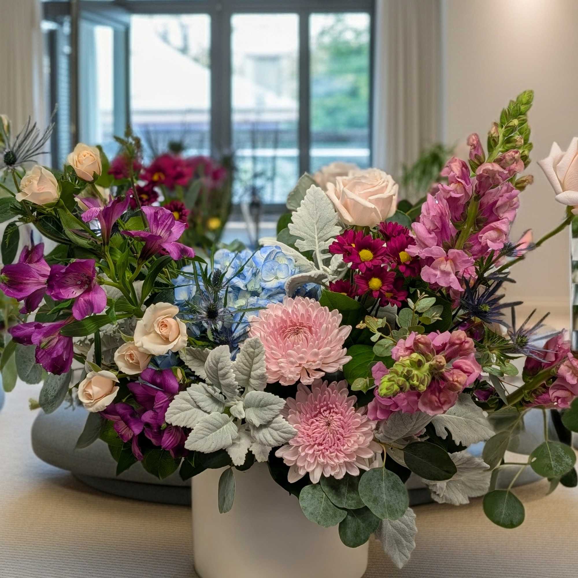 Mixed bouquet in a white vase with pink, purple, and blue flowers