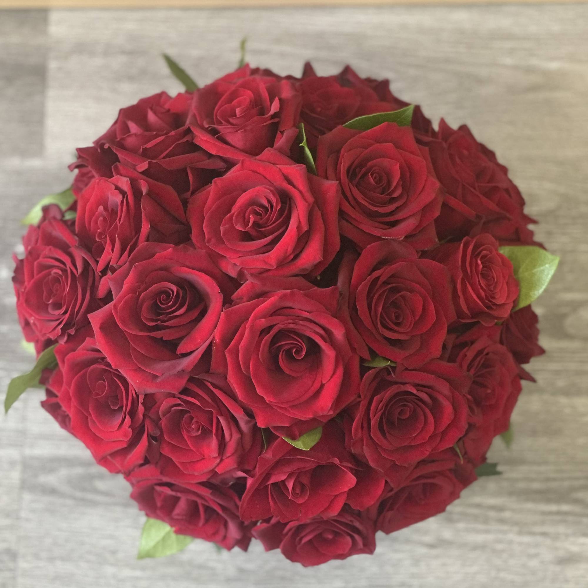 Round bouquet of red roses with a few green leaves