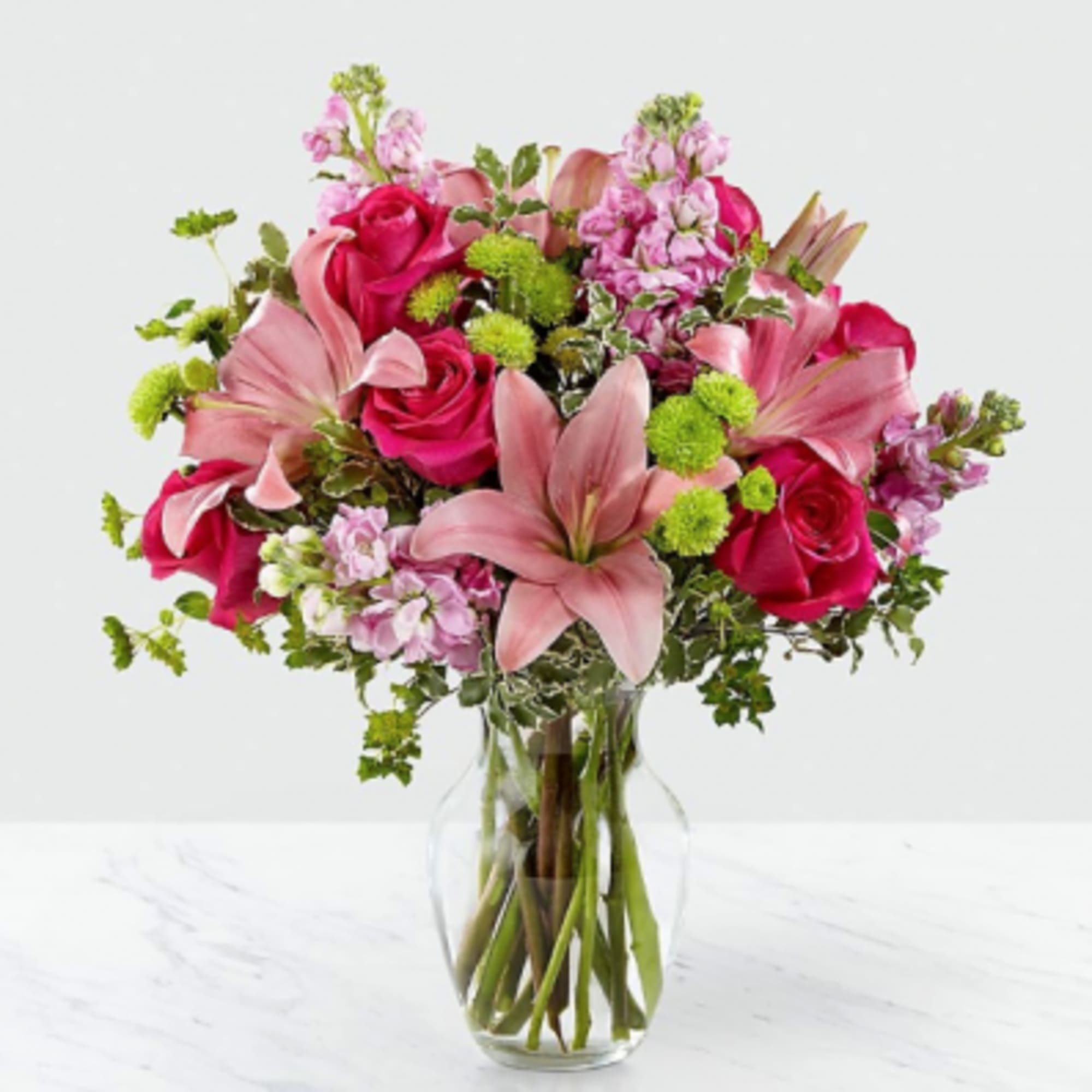 Pink roses and lilies arranged in a clear glass vase