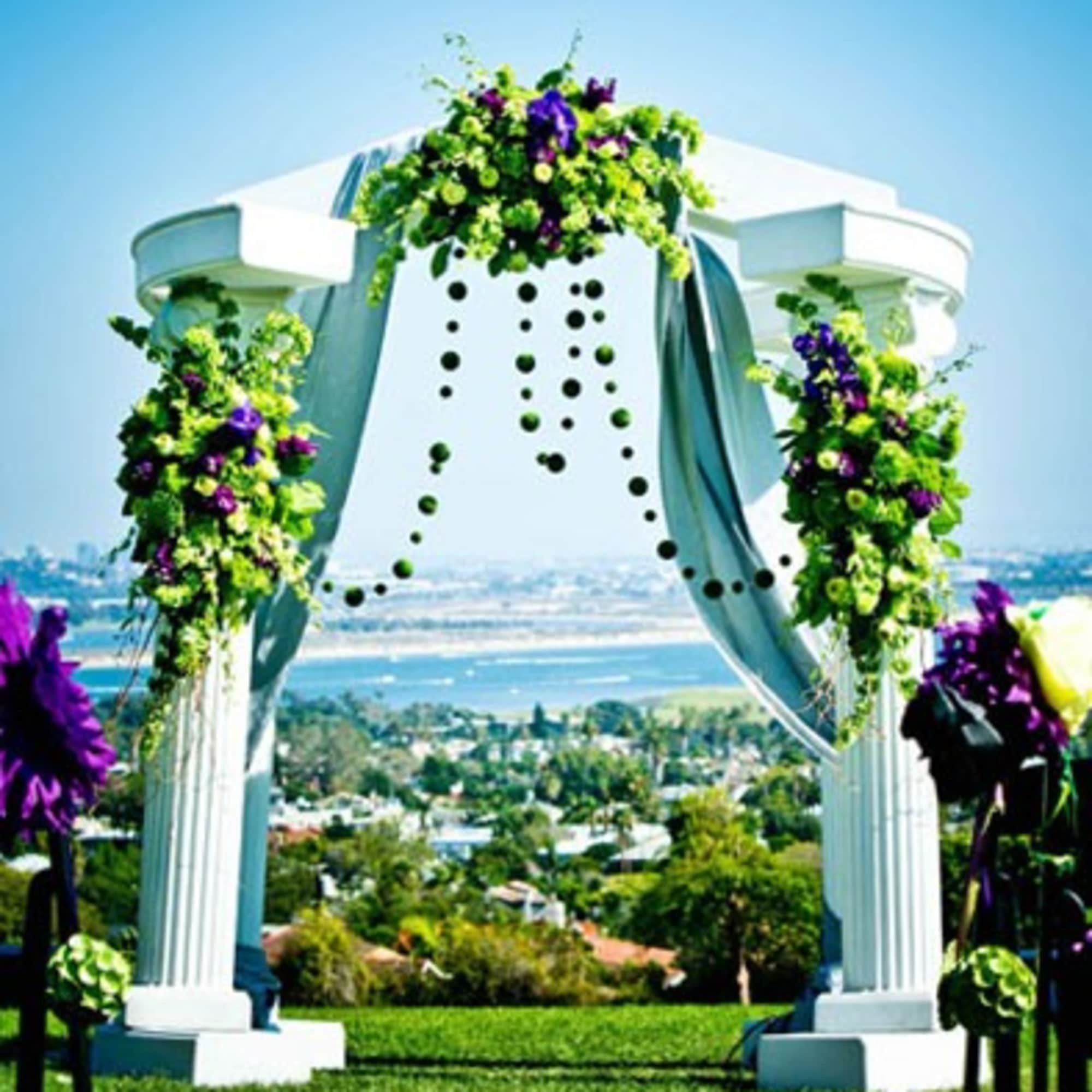 Floral arch with green and purple arrangements and draped fabric outdoors
