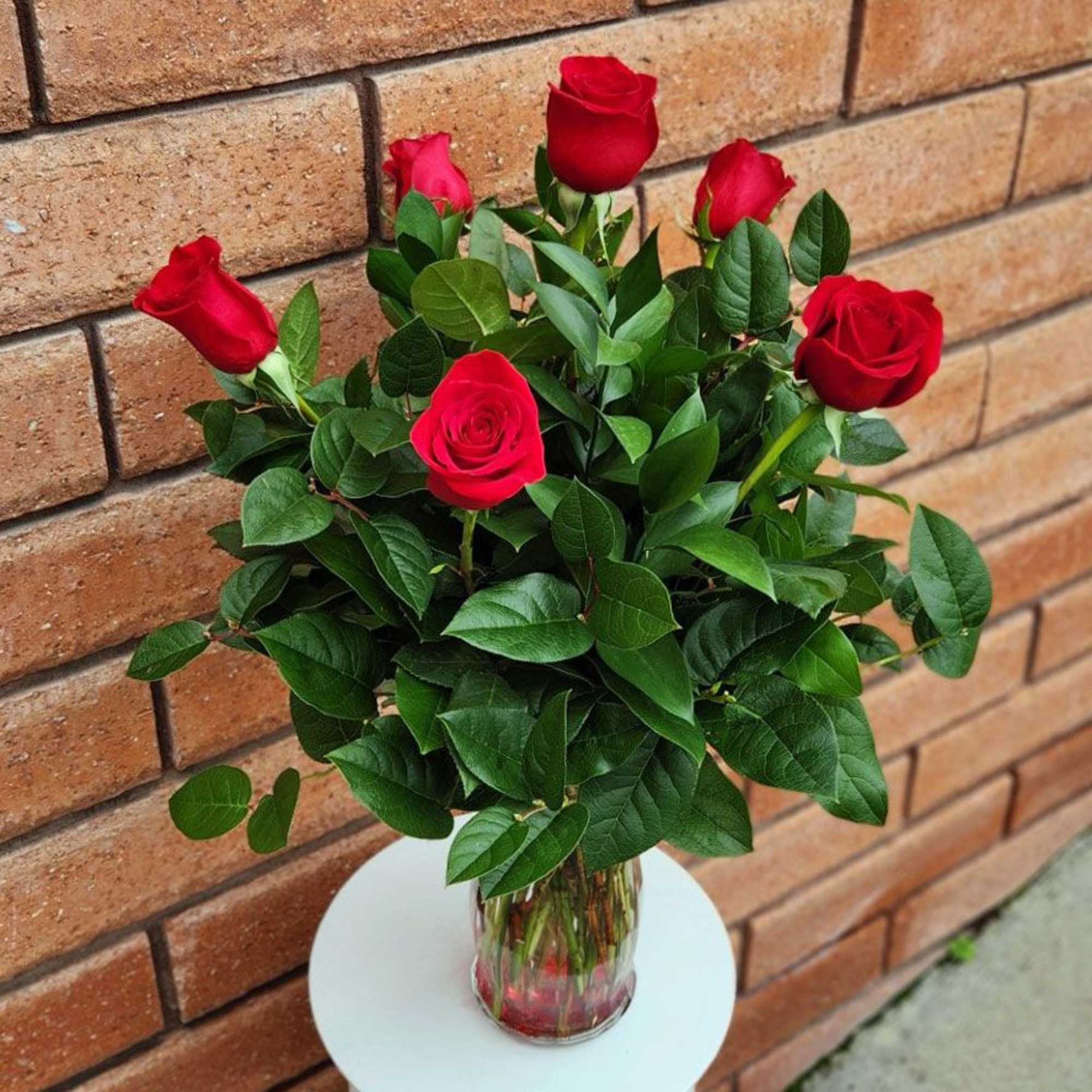 Red roses arranged in a clear glass vase