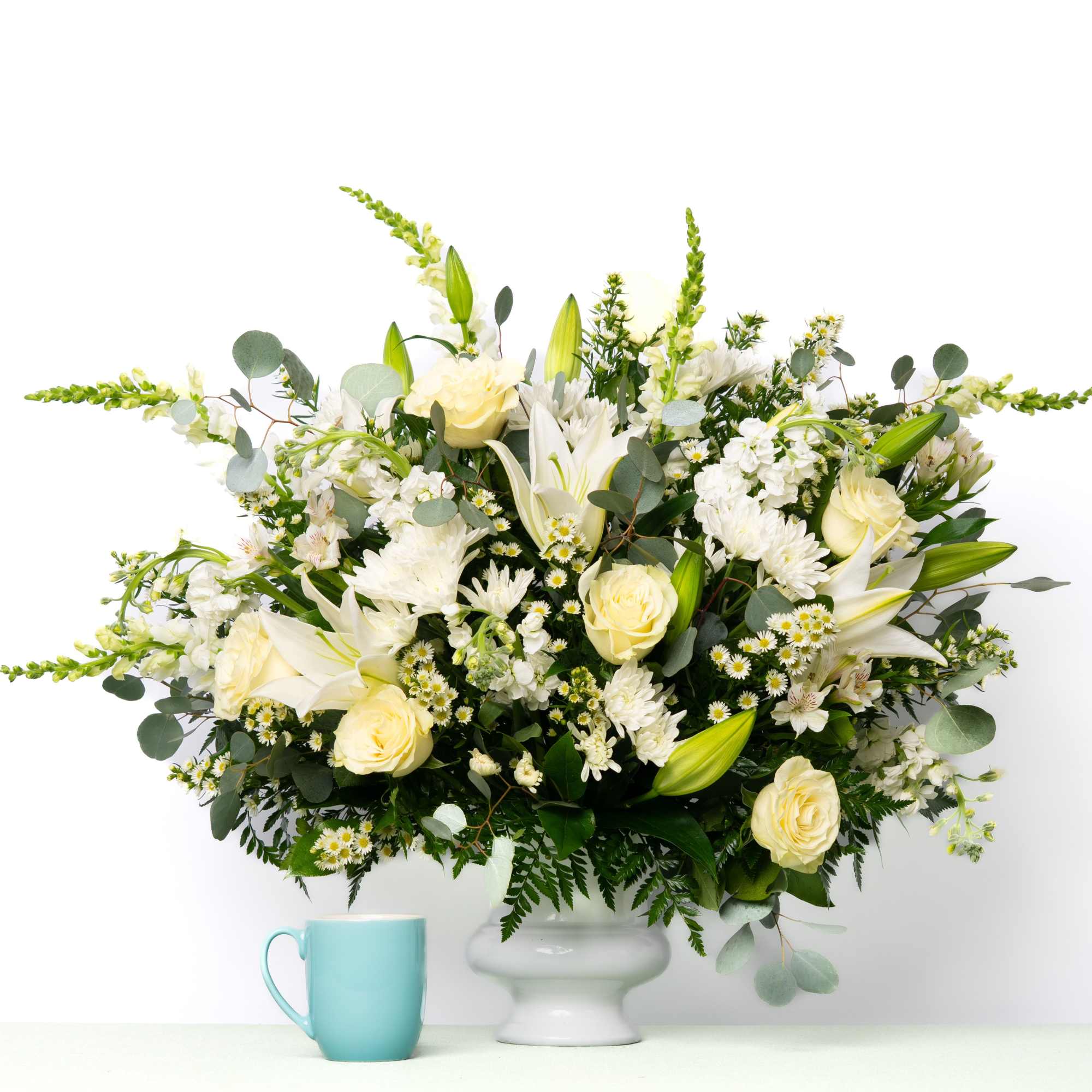 Designed to surround the urn with understated elegance, this best-selling all-white arrangement