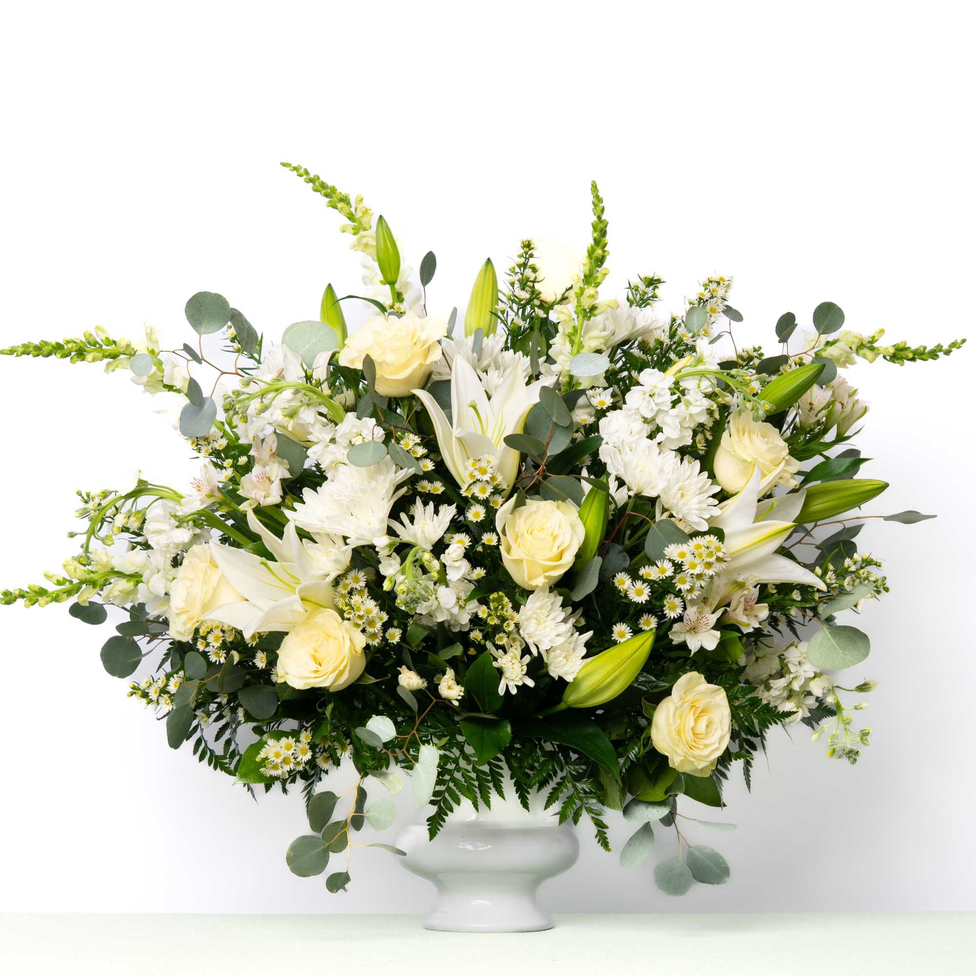 Designed to surround the urn with understated elegance, this best-selling all-white arrangement