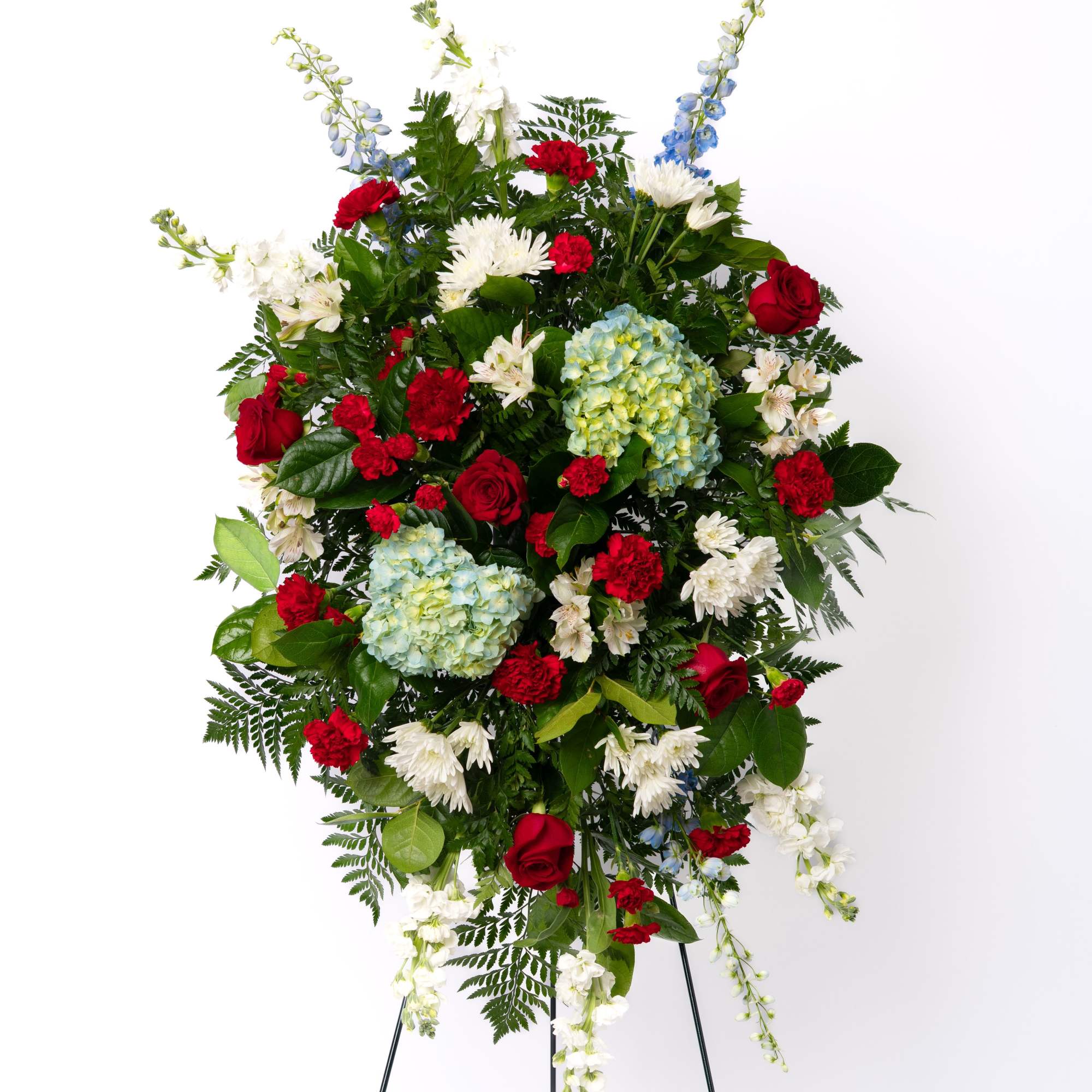 Tall red, white, and blue standing spray with roses, hydrangeas, and mums on a metal easel